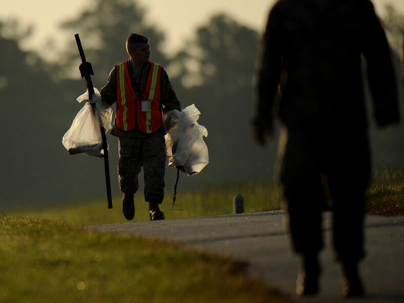 MOODY AIR FORCE BASE, Ga. -- An Airman holds a bag of foreign objects and follows behind a line of Airmen during a foreign object debris walk here June 19. Airmen who participated in the FOD walk were from numerous squadrons around the base. (U.S. Air Force photo by Senior Airman Gina Chiaverotti)
