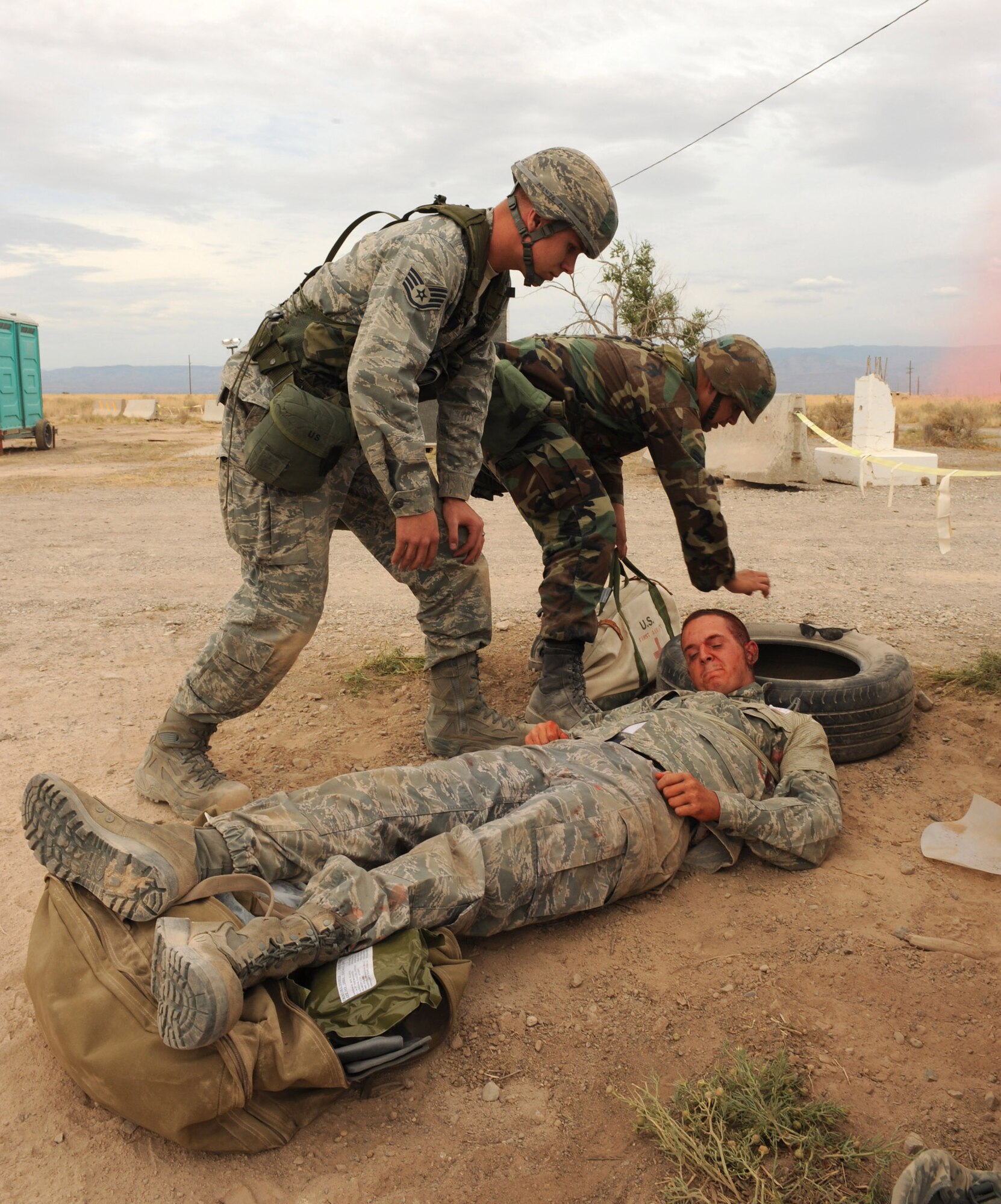 Members from Team Holloman arrive at the scene of a ground attack on the Civil Engineer Pit to perform self-aid and buddy care to a casualty with a simulated gunshot wound June 18 at Holloman Air Force Base, N.M. The Airmen treat his wound and transported him back to the medical tent during exercise Coronet Gold Rush 09-06. (U.S. Air Force photo/Airman 1st Class Sondra Escutia)
