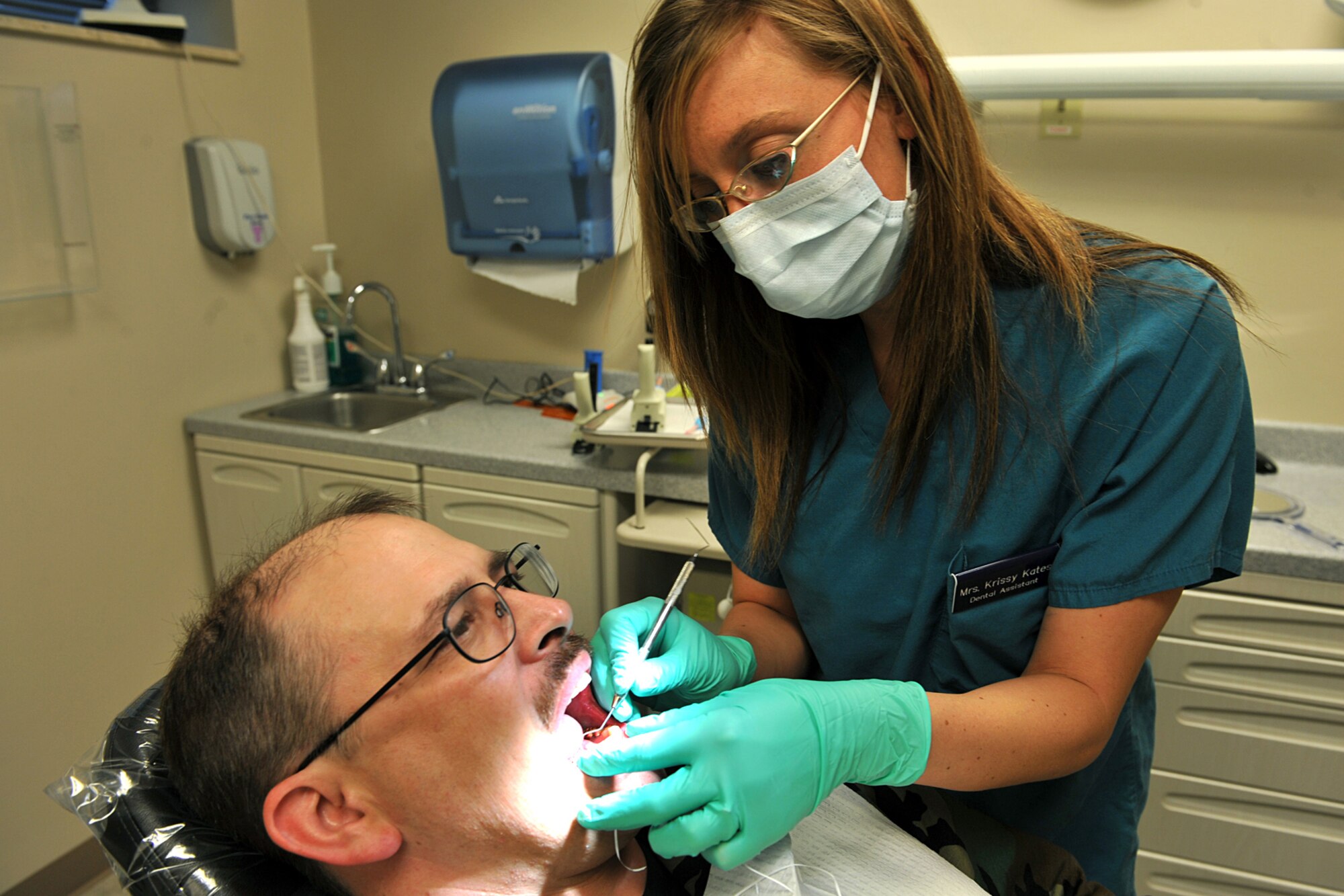OFFUTT AIR FORCE BASE Neb,. -- Krissy Kates, dental assistant with the 55th Dental Squadron, examines the teeth of Tech. Sgt. Dennis Heck, 55th Communications Group, inside the dental facility at the Ehrling Bergquist Clinic here April 26. The 55th Medical Group scored an outstanding rating on their recent Health Services Inspection becoming the first unit in the continental United States to do so this year. U.S. Air Force Photo by Charles Haymond