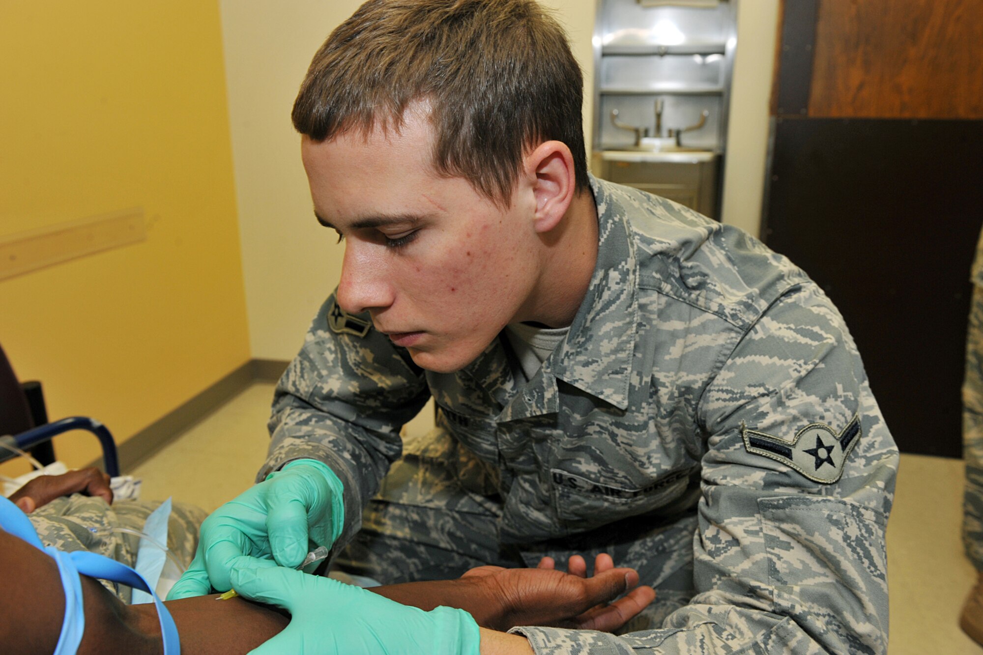 OFFUTT AIR FORCE Neb,.-- Airman Zachary Griffith, 55th Medical Group, searches for a vein in the arm of Airman 1st Class Isaac Zawolo, 55th Medical Group, before administering intravenous therapy inside the Ehrling Bergquist Clinic here April 26. The 55th MDG scored an outstanding rating on their recent Health Services Inspection becoming the first unit in the continental United States to do so this year. U.S. Air Force Photo by Charles Haymond