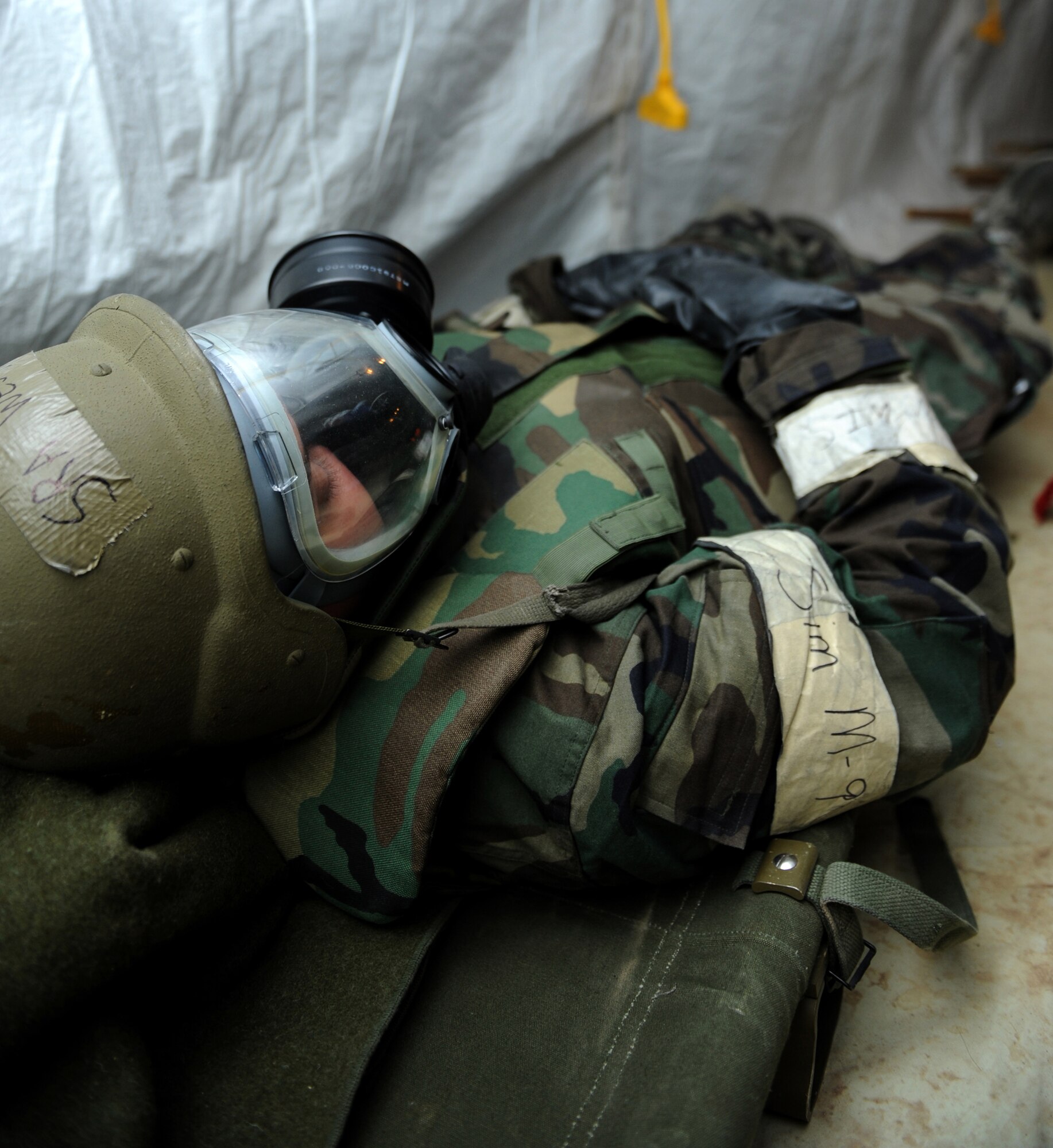 Senior Airman Jeromey West, 49th Aeromedical Dental Squadron, simulates a patient in the medical tent while wearing Mission Oriented Protective Posture level 4 at the Civil Engineer Pit, June 17, at Holloman Air Force Base, N.M. Airman West stayed in MOPP 4, which includes a chemical suit, boots, gloves and gas mask, until the simulated chemical attack was over during the Phase II operational readiness exercise. (U.S. Air Force photo/Airman 1st Class Sondra Escutia)