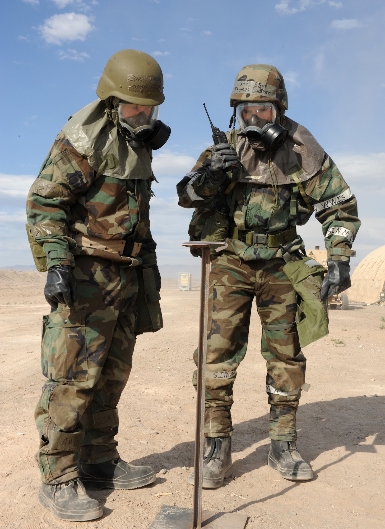 Airman 1st Class Jason Endicott, 49th Contracting Squadron, and Staff Sgt. Thomas Buckner, 49th Comptroller Squadron, report to their Unit Control Center after finding no simulated contamination on the chemical stand outside their tent at the Civil Engineer Pit, June 17, at Holloman Air Force Base, N.M. The Airmen were performing a post-attack reconnaissance sweep in Mission Oriented Protective Posture level 4 after a simulated chemical attack during the Phase II operational readiness exercise. (U.S. Air Force photo/Airman 1st Class Sondra Escutia)