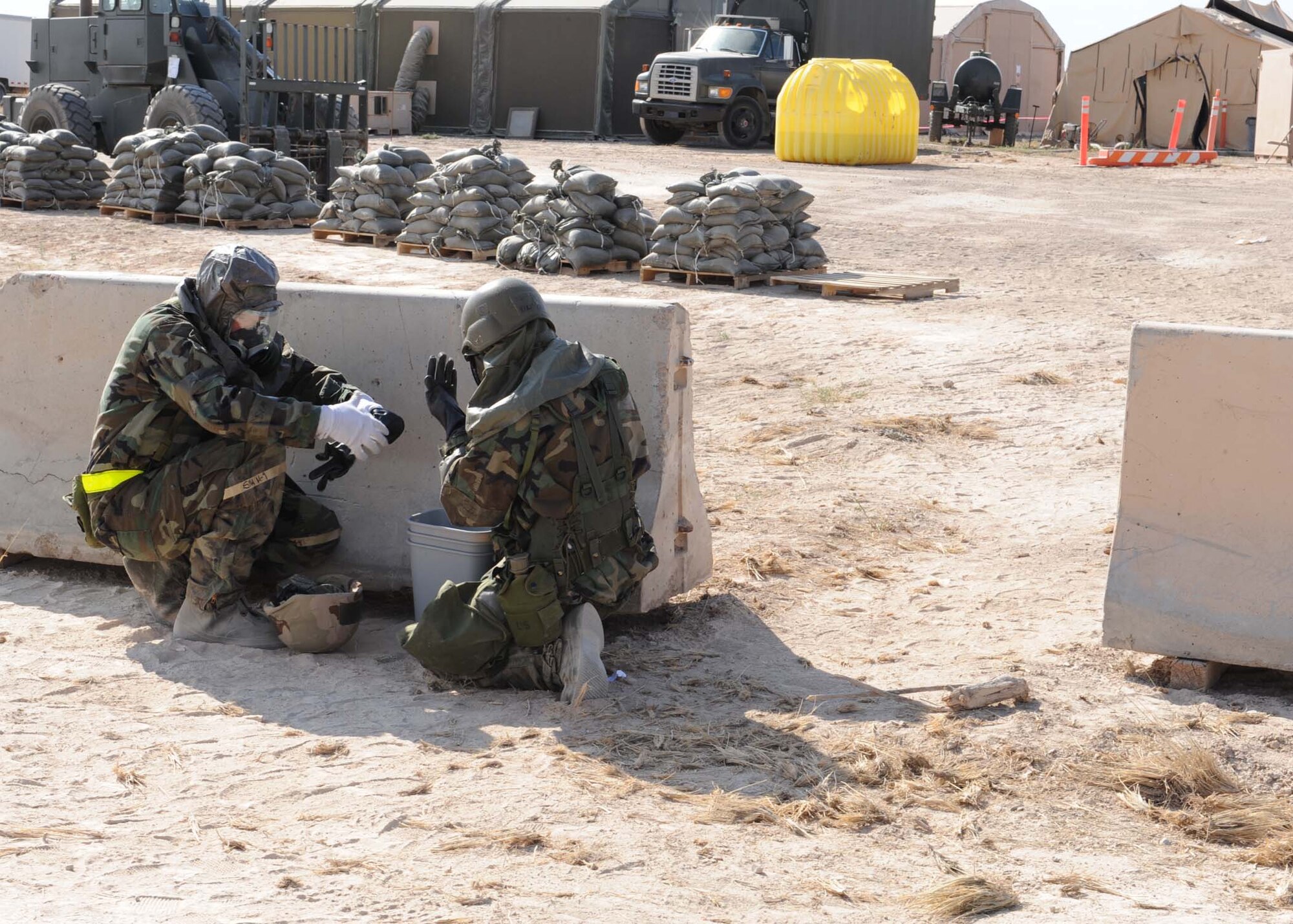 Members of Team Holloman take cover and suit up to Mission Oriented Protective Posture level 4 during a simulated chemical attack during the Phase II operational readiness exercise at the Civil Engineer pit, June 17, at Holloman Air Force Base, N.M. The exercise was desidned to prepare the base personnel for future deployments. (U.S. Air Force photo by Senior Airman Rachel Kocin)