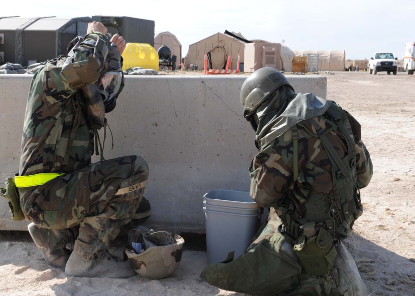 Members of Team Holloman take cover and suit up to Mission Oriented Protective Posture level 4 during a simulated chemical attack at the Civil Engineer Pit, June 17, at Holloman Air Force Base, N.M. MOPP 4 includes chemical suit, mask, gloves and boots. Members donned the gear during the Phase II operational readiness exercise to make sure they knew the proper way to wear their equipment. (U.S. Air Force photo by Senior Airman Rachel Kocin)