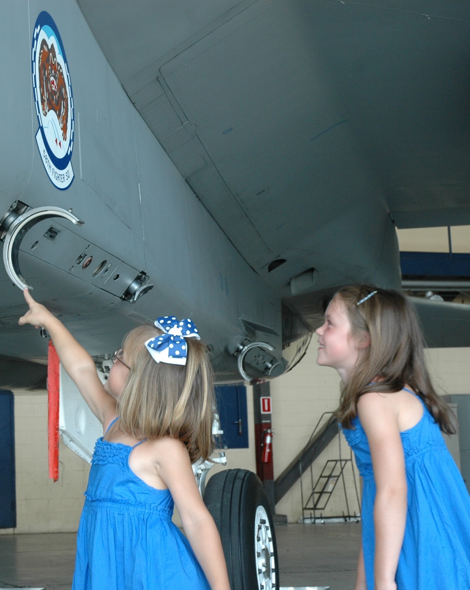Ellie reaches up to touch the F-15 while her sister Abbie watches during the 58th Fighter Squadron reunion June 18 at Eglin Air Force Base, Fla. The six and eight year old daughters of the commander of the 58th, Lt. Col. Mark O'Laughlin dressed up in the unit's colors while attending their open house. A week-long reunion gave past and present squadron members an opportunity to participate in social activities and reminisce about their history while also saying good bye to 30 years of flying the F-15 as they transition to the F-35. (U.S. Air Force photo/Chrissy Cuttita.)
