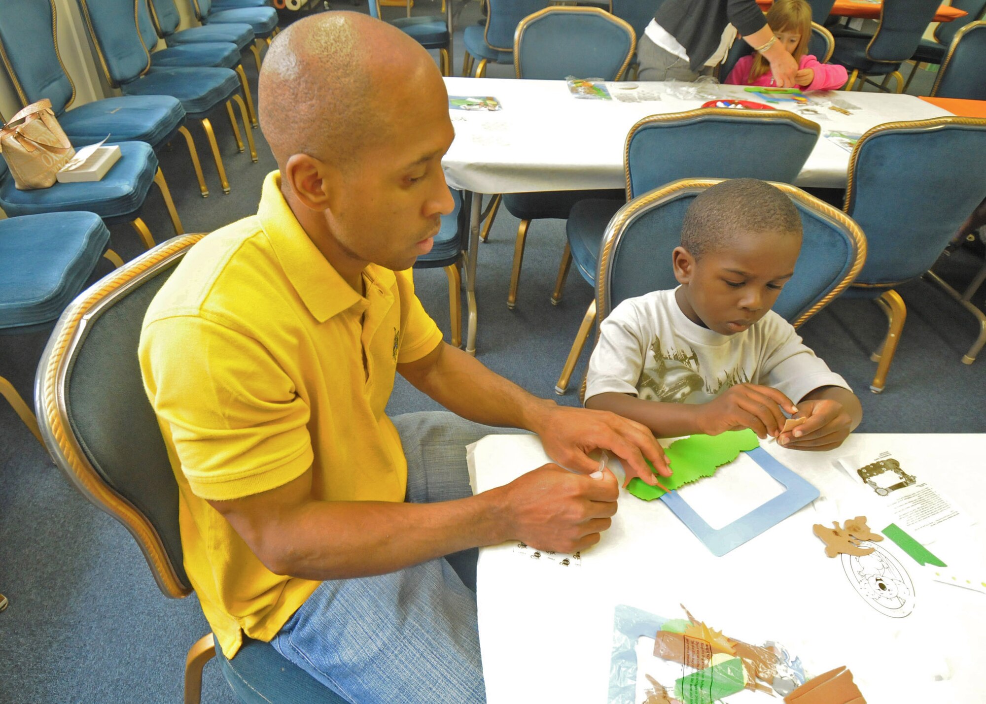 YOKOTA AIR BASE, Japan -- Tech. Sgt. James Gaymon Jr., 374th Airlift Wing command post, and son James III, piece together a picture frame during an Australian-themed craft day at the base library's summer reading program, June 18. Each year the Air Force conducts a summer reading program for children of military members to help improve their reading proficiency. This year's theme is Book-A-Trip: Read Around the World. (U.S. Air Force photo/Staff Sgt. Veronica Pierce)