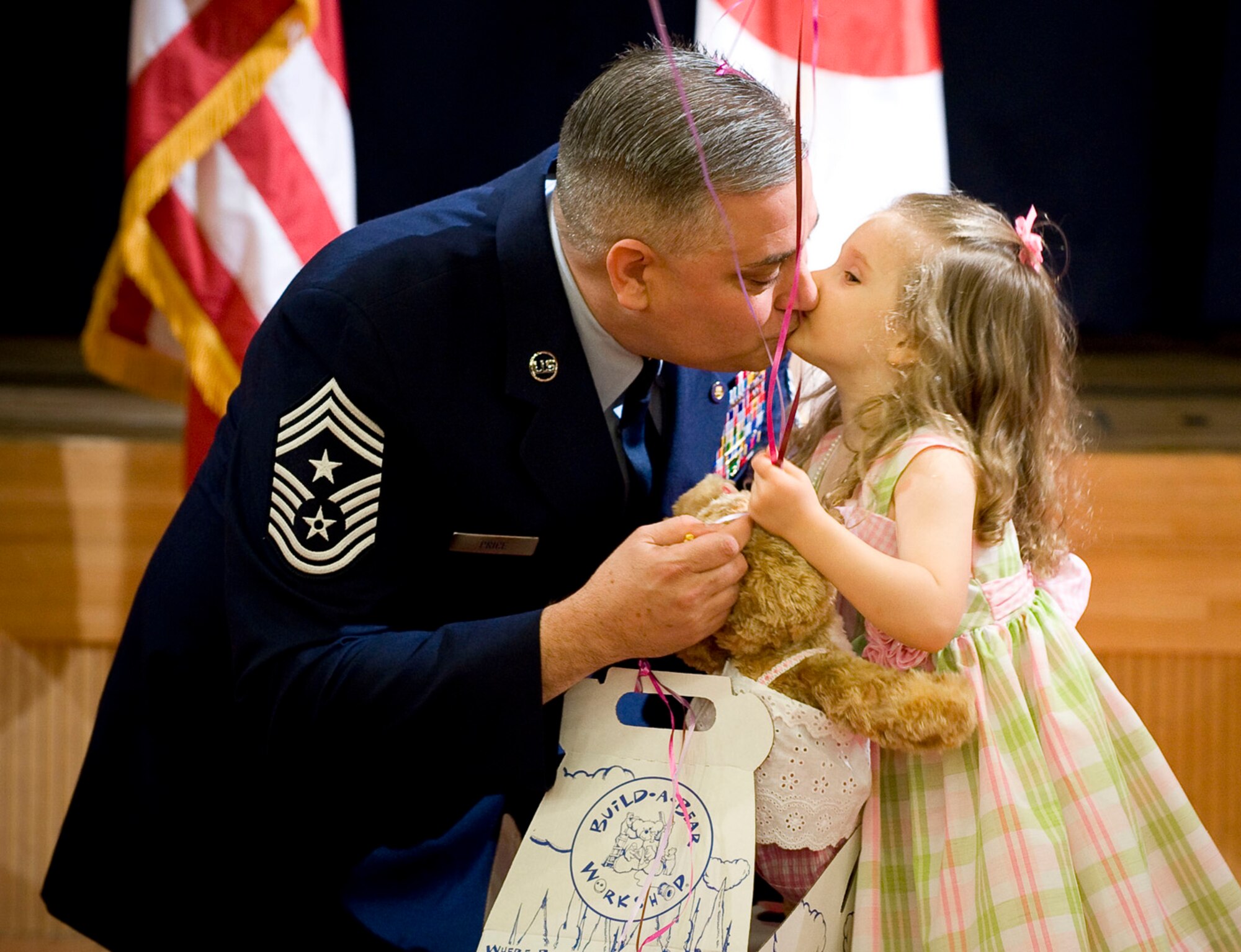 MISAWA AIR BASE, Japan -- Chief Master Sgt. Ricky Price kisses his daughter, Makayla, after giving her a bear during his retirement ceremony June 19, 2009. Chief Price made the bear and named it "Moody" which is a name synonymous with kisses and love in the Price household. (U.S. Air Force photo by Staff Sgt. Samuel Morse)