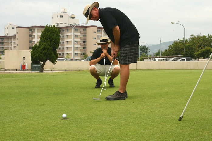Stephen Regonini putts for par on the 26th hole at the Torii Pines Golf Course here June 20 during the 2009 Summer Solstice Golf Tournament. Teammate and friend Jeremy Soeken watches as the ball nears the hole,::r::::n::knowing that he will have to make the same shot as part of the second section of the tournament called the Scramble.