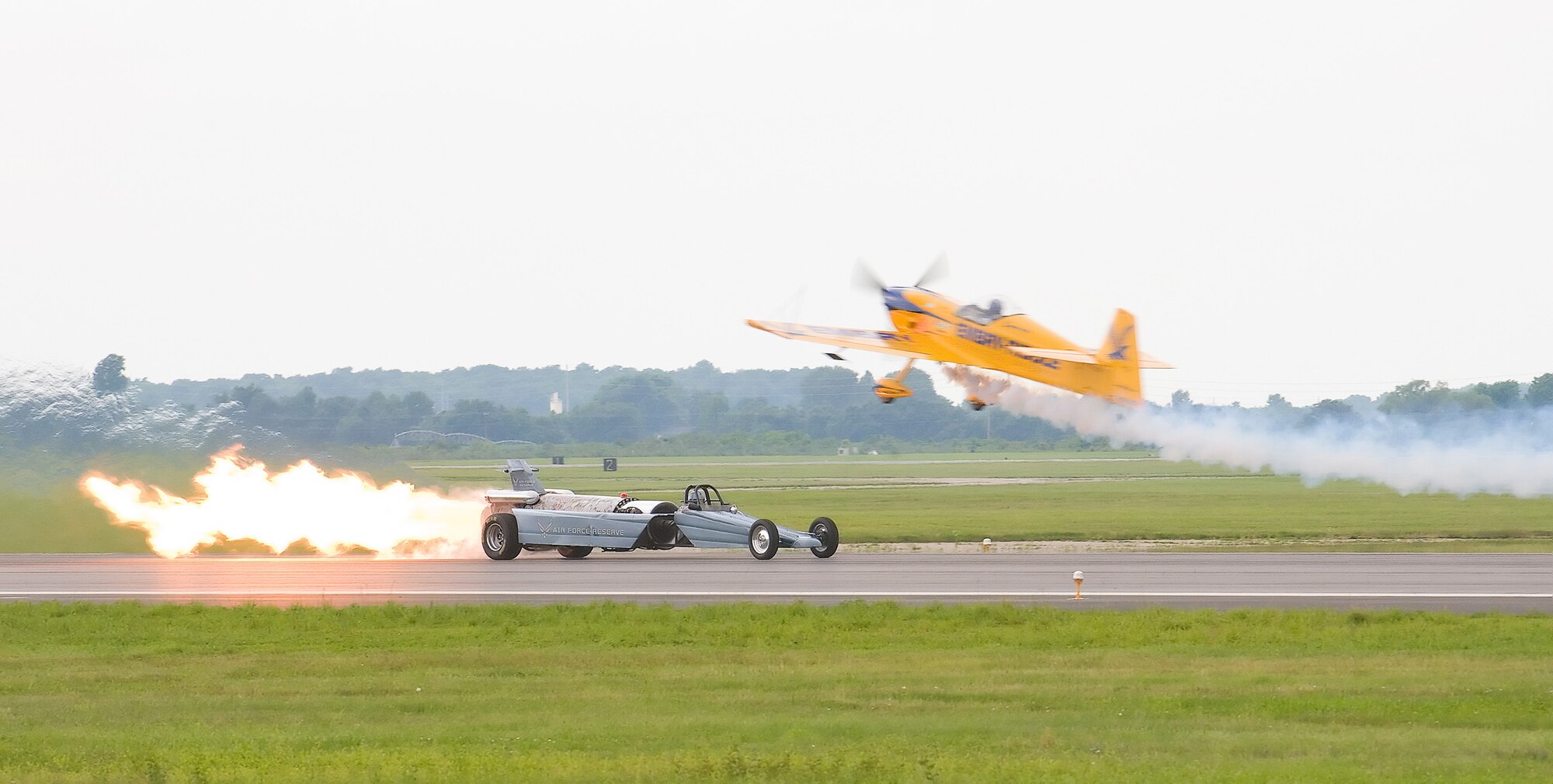 Matt Chapman flies his Embry-Riddle Eagle 580 over the Air Force Reserve Jet car at the Dover Air Force Base Open House and Air Show June 21. Mr. Chapman raced the jet car down the Dover runway, losing to the car, which traveled at speeds in excess of 380 miles per hour. (U.S. Air Force photo/Tom Randle)