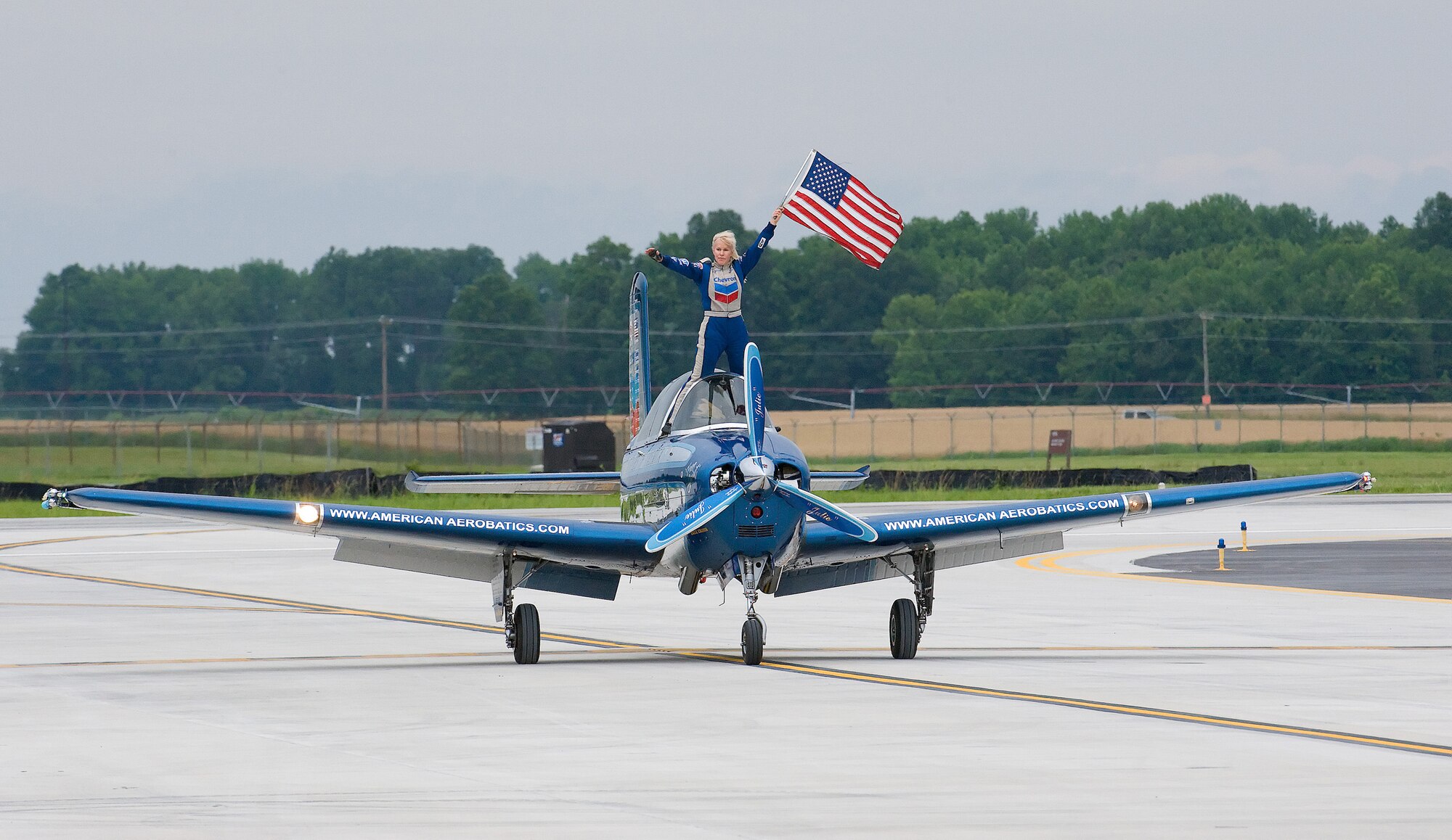 Julie Clark holds an American flag as her T-34A Mentor is piloted down the runway at Dover Air Force Base June 21. Ms. Clark was one of the 14 aerial demonstrations that participated in the Dover AFB Open House and Air Show. (U.S. Air Force photo/Tom Randle)