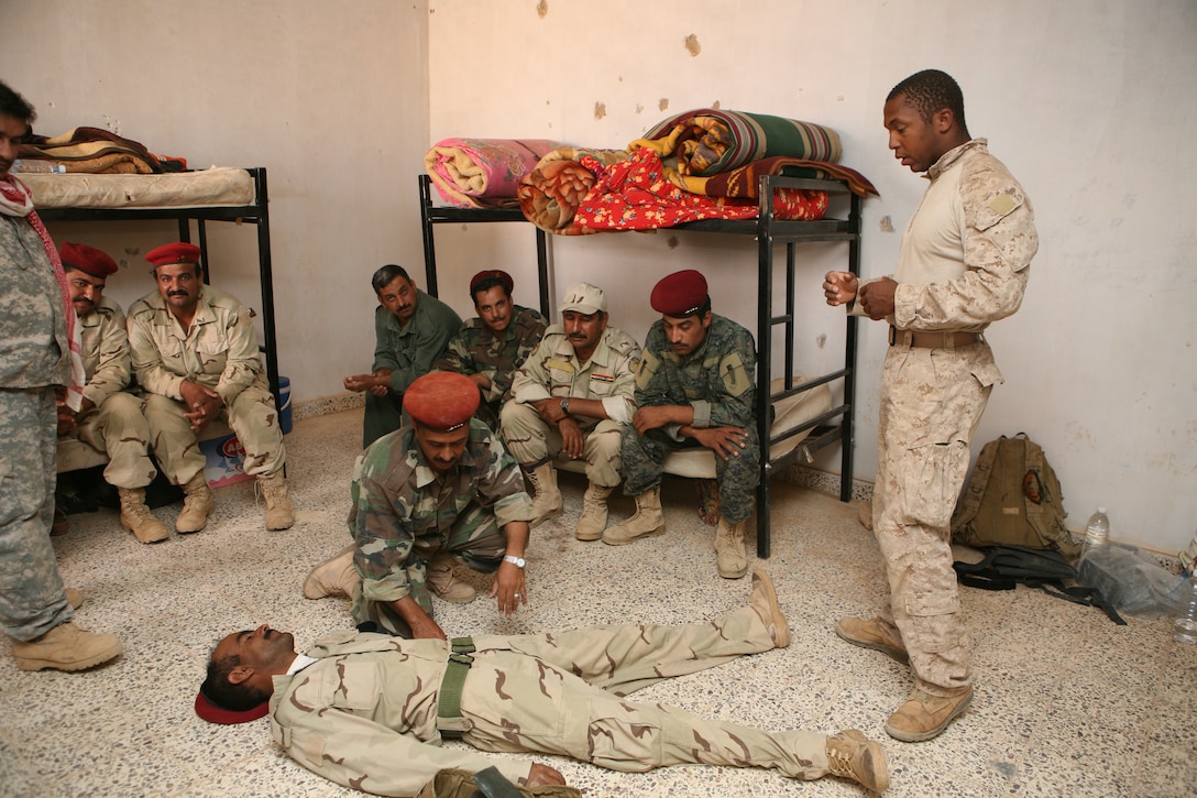 Iraqi soldiers listen as Petty Officer 2nd Class Aaron Ward, corpsman for Bravo Company, 2nd Reconnaissance Battalion, Regimental Combat Team 8, explains the necessary steps to take when dealing with an unconscious victim June 22-24, 2009, at Mudaysis Airfield, Iraq.  Ward, along with Marines from 2nd Recon, led the Iraqi soldiers through a variety of combat lifesaving training classes during their three-day course.