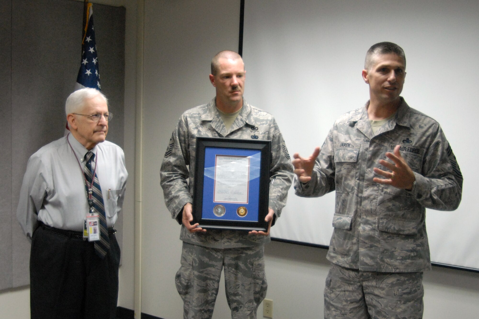 Chief Master Sgt. Eric Jaren (right), 95th Air Base Wing command chief, presents a a letter of appreciation and talks briefly June 21 about Joint Test, Training and Tactics' effort during the First Sergeant's Council holiday season fund raiser. Master Sgt. Bobby Herron (center), 95th Security Forces Squadron first sergeant, proffers for the presentation to Jim Tedeschi (left), JT3 Range manager.  JT3 raised $2,500 in contributions during the September 2008 fund raiser. The money raised helped support Edwards Airmen during the holiday season with interest-free loans, grants and food gift certificates.(Air Force photo/Airman 1st Class William O'Brien)