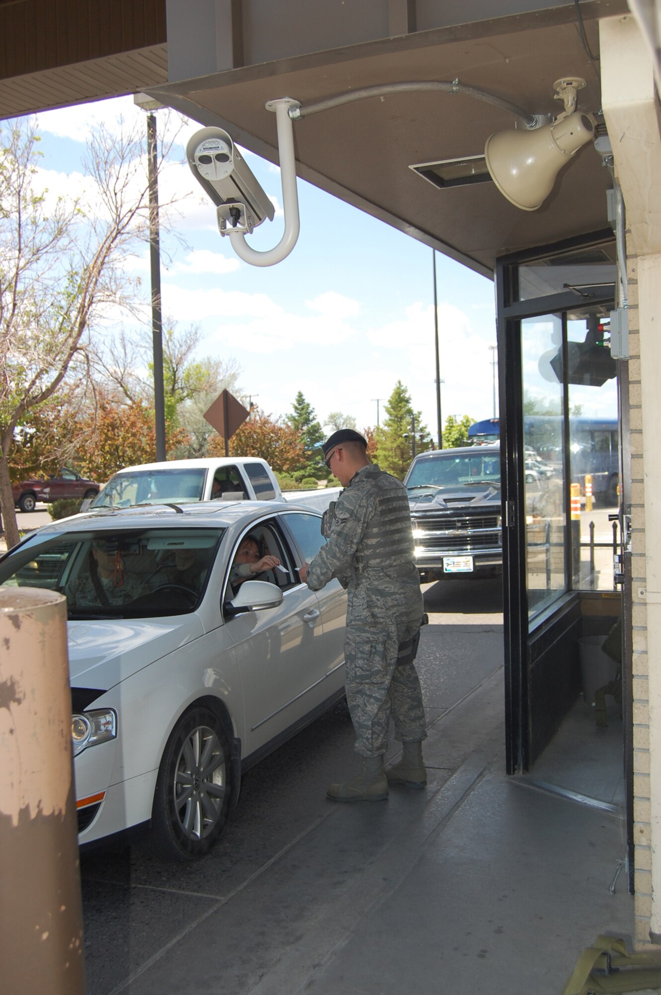 Airman 1st Class Nathan Topliff, 341st Security Force Squadron gate guard, checks the IDs of military members entering Malmstrom. The forward photo-taking camera and the horn that sounds for tagged vehicles are also pictured mounted to the front of the guard facility. (U.S. Air Force photo/Valerie Mullett) 