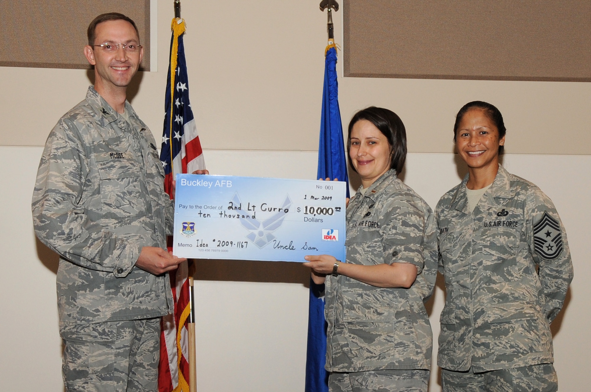 BUCKLEY AIR FORCE BASE, Colo. – 2nd Lt. Shawn Curro was awarded a $10,000 check from the Air Force Innovative Development through Employee Awareness Program during the 460th Space Wing commander’s call here, June 11.  Col. Wayne McGee, 460th SW commander, and Chief Master Sgt. Arleen Heath, 460th SW Command Chief presented the check on behalf of the IDEA Program.  The program rewards Airmen for ideas that save Air Force money and resources.  (U.S. Air Force photo by Senior Airman John Easterling)
