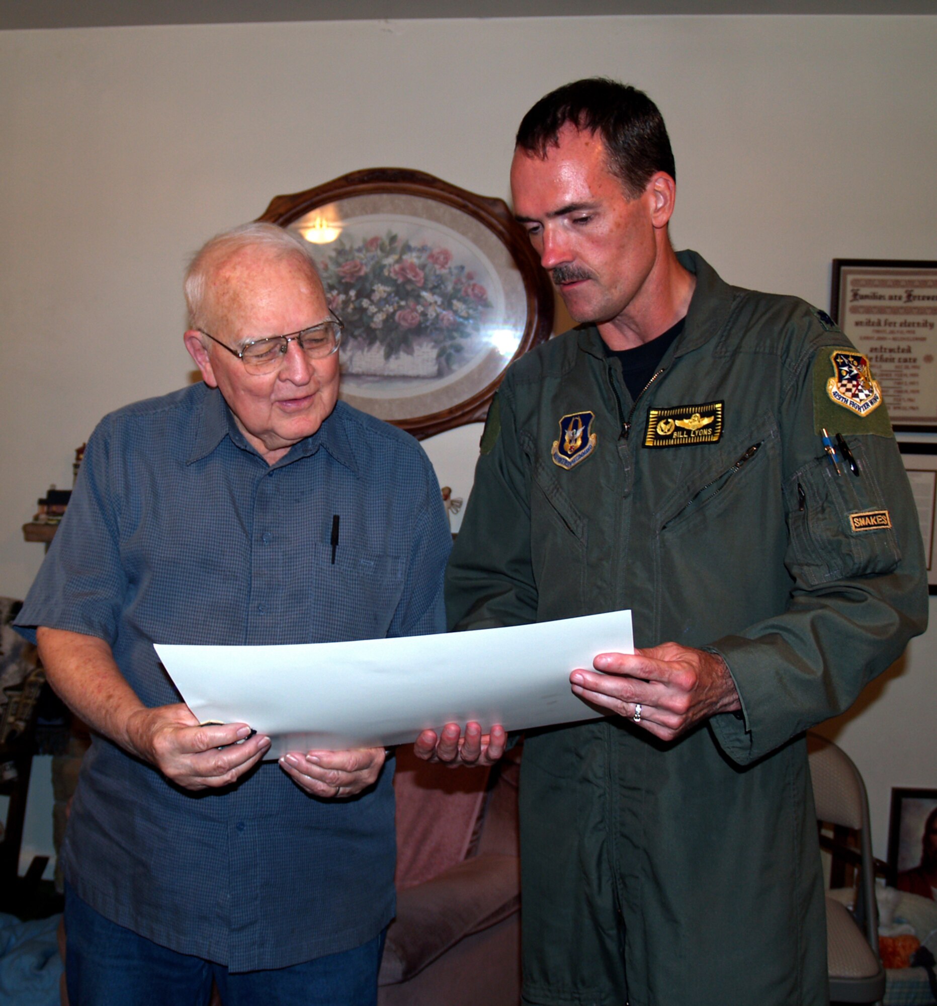 Lt. Col. Bill Lyons, 419th Operations Group commander, presents Grant Harris, a World War II veteran and fellow fighter pilot, with a lithograph from the 466th Fighter Squadron. (U.S. Air Force photo/Bryan Magaña)