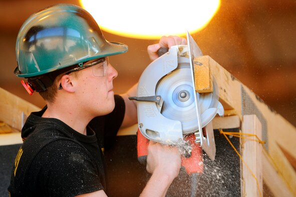U.S. Air Force Academy Cadet 2nd Class Drew Miller cuts a two-by-four during a Field Engineering and Readiness Laboratory activity June 5. Cadets learned skills such as surveying, concrete placement and a self-help project at billeting that will save $40,000 per year in laundry costs. (U.S. Air Force photo/Dave Ahlschwede)
