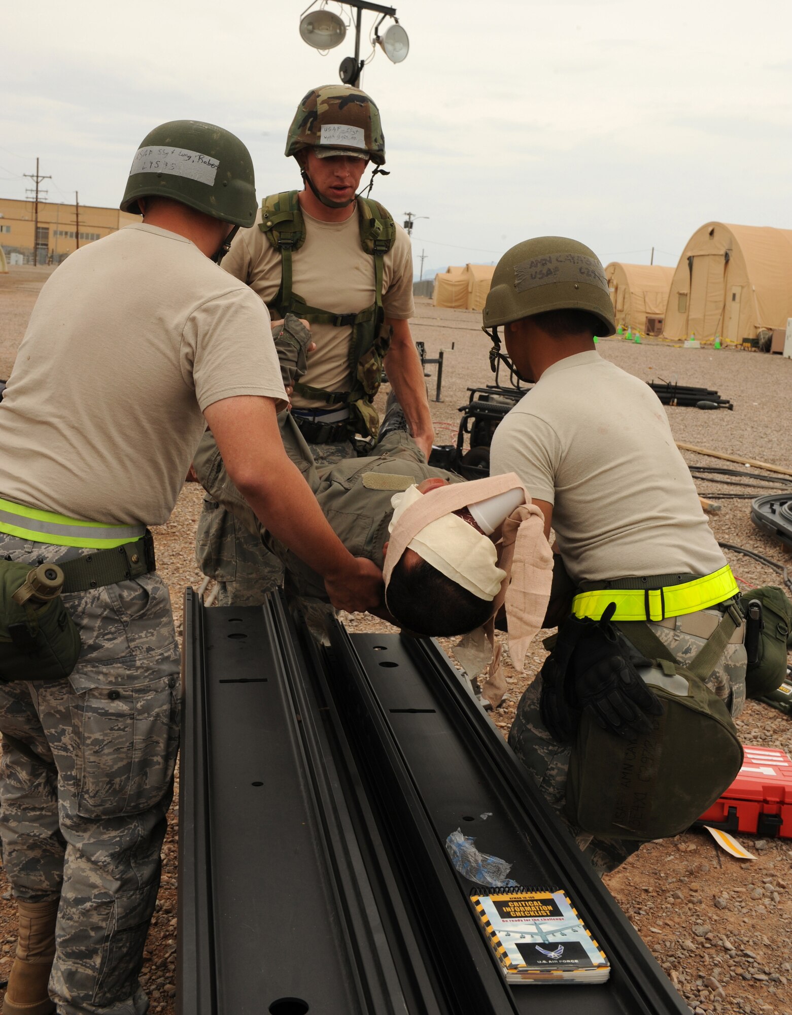 Airmen from the 49th Materiel Maintenance Squadron perform a three-man carry on a simulated causality who suffered trauma to his right eye and face after an attack on Basic Expeditionary Airfield Resources Base, June 18, at Holloman Air Force Base, N.M, during exercise Coronet Gold Rush 09-06. The Airmen proceeded to put him in the back of a truck and transported him to the Civil Engineer Pit where medics simulated treating him further. (U.S. Air Force photo/Airman 1st Class Sondra Escutia)