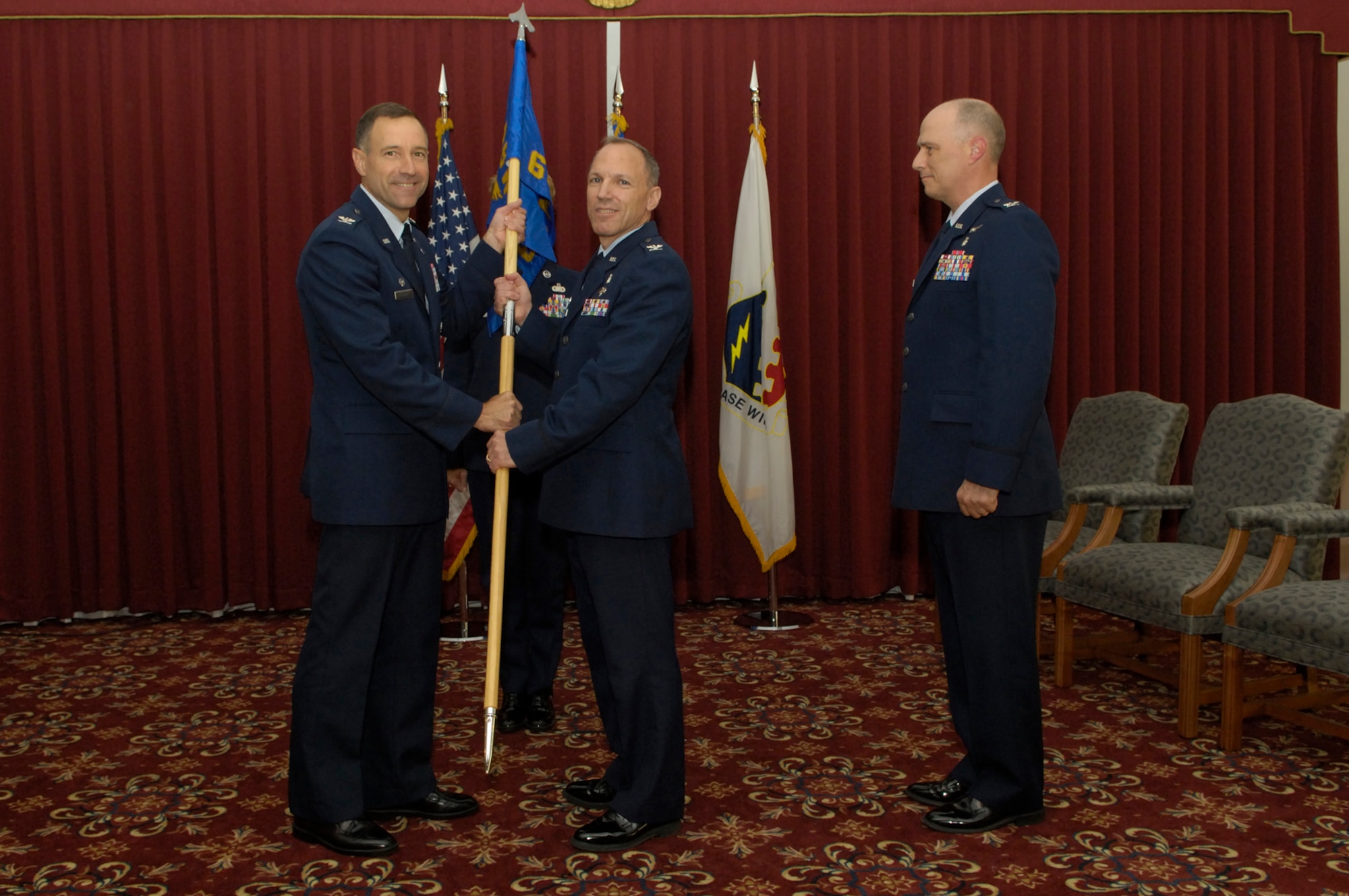 HANSCOM AIR FORCE BASE, Mass. -- Col. Parker Plante, commander of the 66th Medical Group, accepts the command guidon from 66th Air Base Wing Commander Col. Dave ‘Iron’ Orr, as outgoing 66 MDG Commander Col. Jackson Dobbins looks on.  The change of command ceremony was held June 17 in the ballroom of the Hanscom Minuteman Club.  Colonel Dobbins retired that same day, following 29 years of Air Force service. (USAF Photo/Mark Herlihy)
