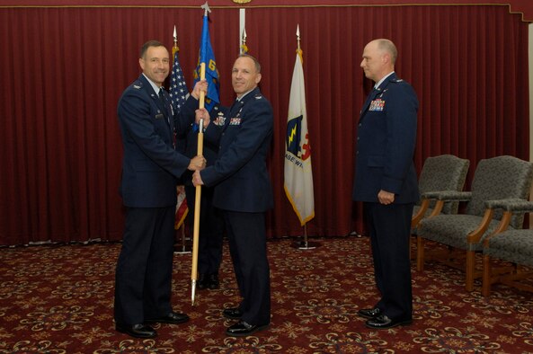 HANSCOM AIR FORCE BASE, Mass. -- Col. Parker Plante (center), commander of the 66th Medical Group, accepts the command guidon from 66th Air Base Wing Commander Col. Dave ‘Iron’ Orr, as outgoing 66 MDG Commander Col. Jackson Dobbins looks on. The change of command ceremony was held June 17 in the ballroom of the Hanscom Minuteman Club. Colonel Dobbins retired that same day, following 29 years of Air Force service. (USAF Photo/Mark Herlihy) 
