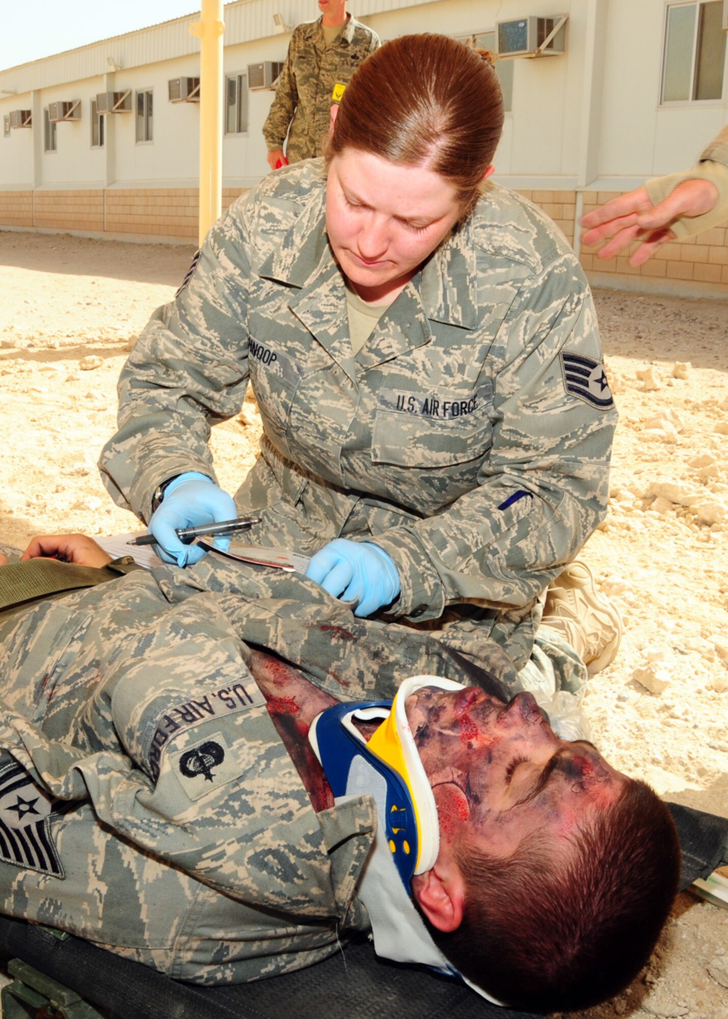 SOUTHWEST ASIA -- Staff Sgt. Betty Schnoop, 386th Expeditionary Medical Group, completes a triage tag for simulated burn victim during a dorm fire exercise at an air base in Southwest Asia, June 22. A triage tag has three basic categories -- a tear off section to label the severity of the patient's injury and status, main body for the patient assessment and peel off sticker to identify what transportation and treatment the patient received. Sergeant Schnoop is deployed from Wright-Patterson Air Force Base, Ohio and hails from Albany, N.Y. (U.S. Air Force photo/Senior Airman Courtney Richardson)