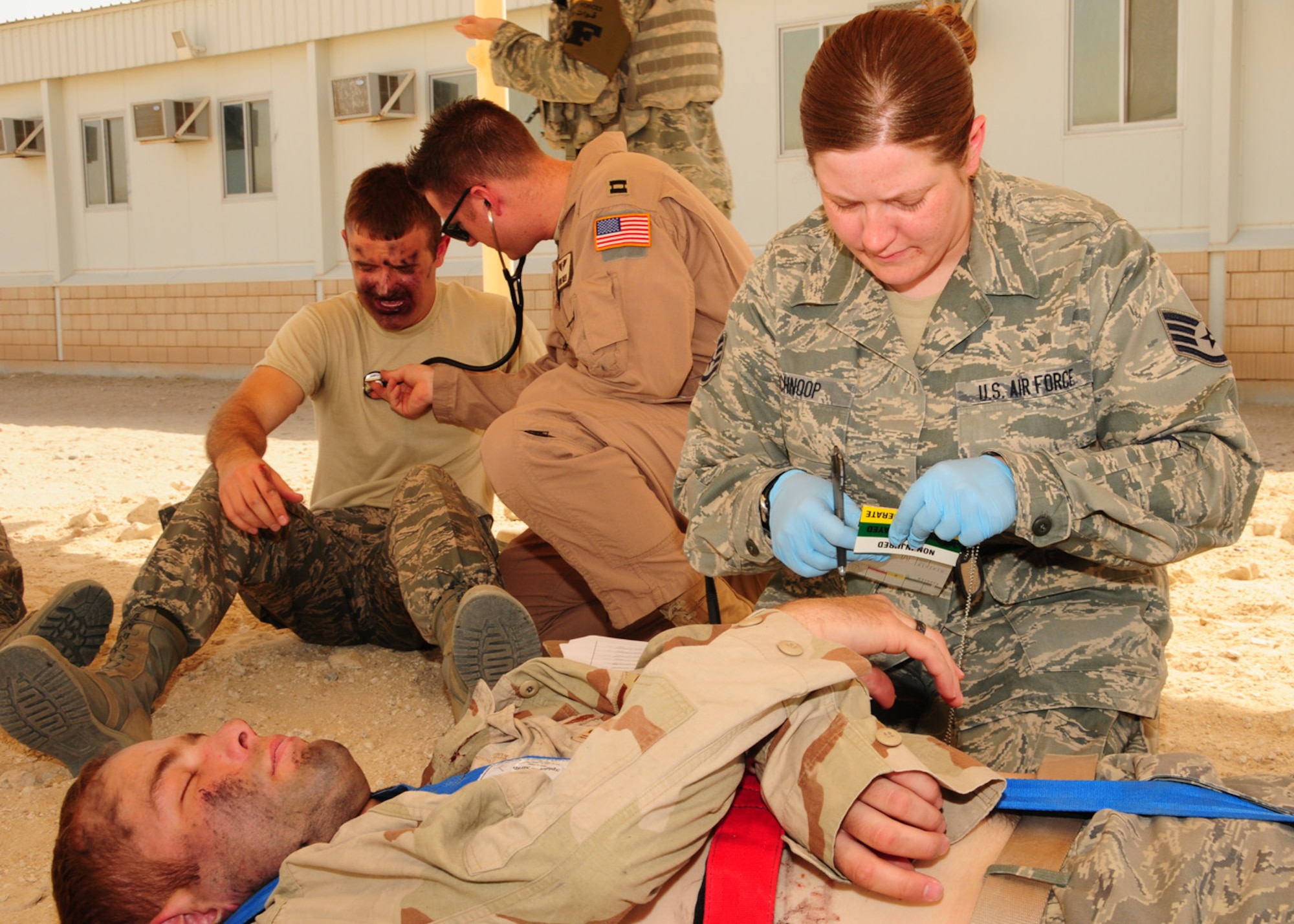 SOUTHWEST ASIA -- Staff Sgt. Betty Schnoop, 386th Expeditionary Medical Group, labels a simulated victim as immediate response, due to a life threatening injury, while Capt. Layne Green, 386th Expeditionary Medical Group, checks the lungs of a simulated burn victim during a dorm fire exercise at an air base in Southwest Asia, June 22. A triage tag is a tool first responders and medical personnel use during mass casualty incidents to identify the victims and to prioritize the severity of their injury. Sergeant Schnoop is deployed from Wright-Patterson Air Force Base, Ohio and hails from Albany, N.Y. and Captain Green is deployed from Brooks City-Base, Texas, and is originally from Meridian, Idaho. (U.S. Air Force photo/Senior Airman Courtney Richardson)
