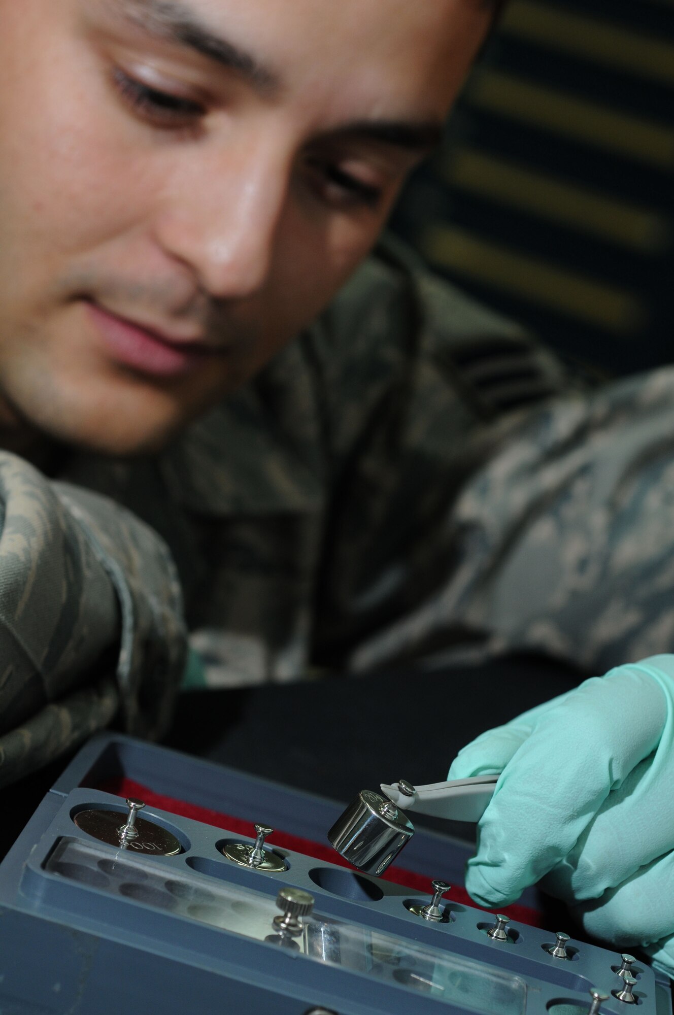YOKOTA AIR BASE, Japan -- Senior Airman Andrew Doman, 374th Maintenance Squadron Precision Measurement Equipment Laboratory technician, visually inspects an S1 weight which is used as a precise weight to calibrate scales June 23. PMEL technicians perform and manage repair on test, measurement, and diagnostic equipment. (U.S. Air Force photo/ Staff Sgt. Veronica Pierce)