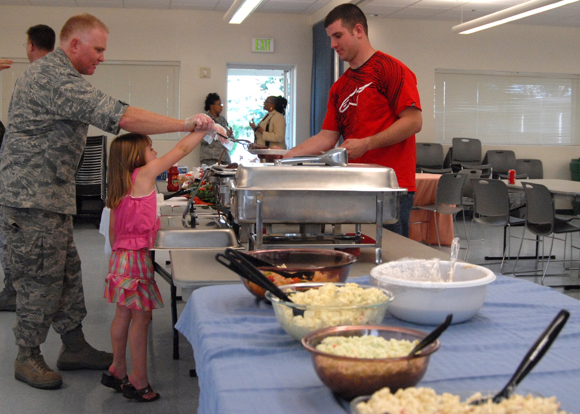 Col. Jerry Gandy, 95th Air Base Wing commander, helps Lexus Shepherd, daughter of Staff Sgt. James Shepherd, member of Edwards Middle-Tier Assocation serve an Airman during the Dorm Dwellers Dinner June 17 at the Chapel 1 annex here. Dorm Dweller Dinners are held every two months to offer a healthy meal to all of Edwards dormitory residents, this dinner was hosted by Edwards Middle-Tier Assocation. (U.S. Air Force photo/Airman 1st Class William O'Brien)  