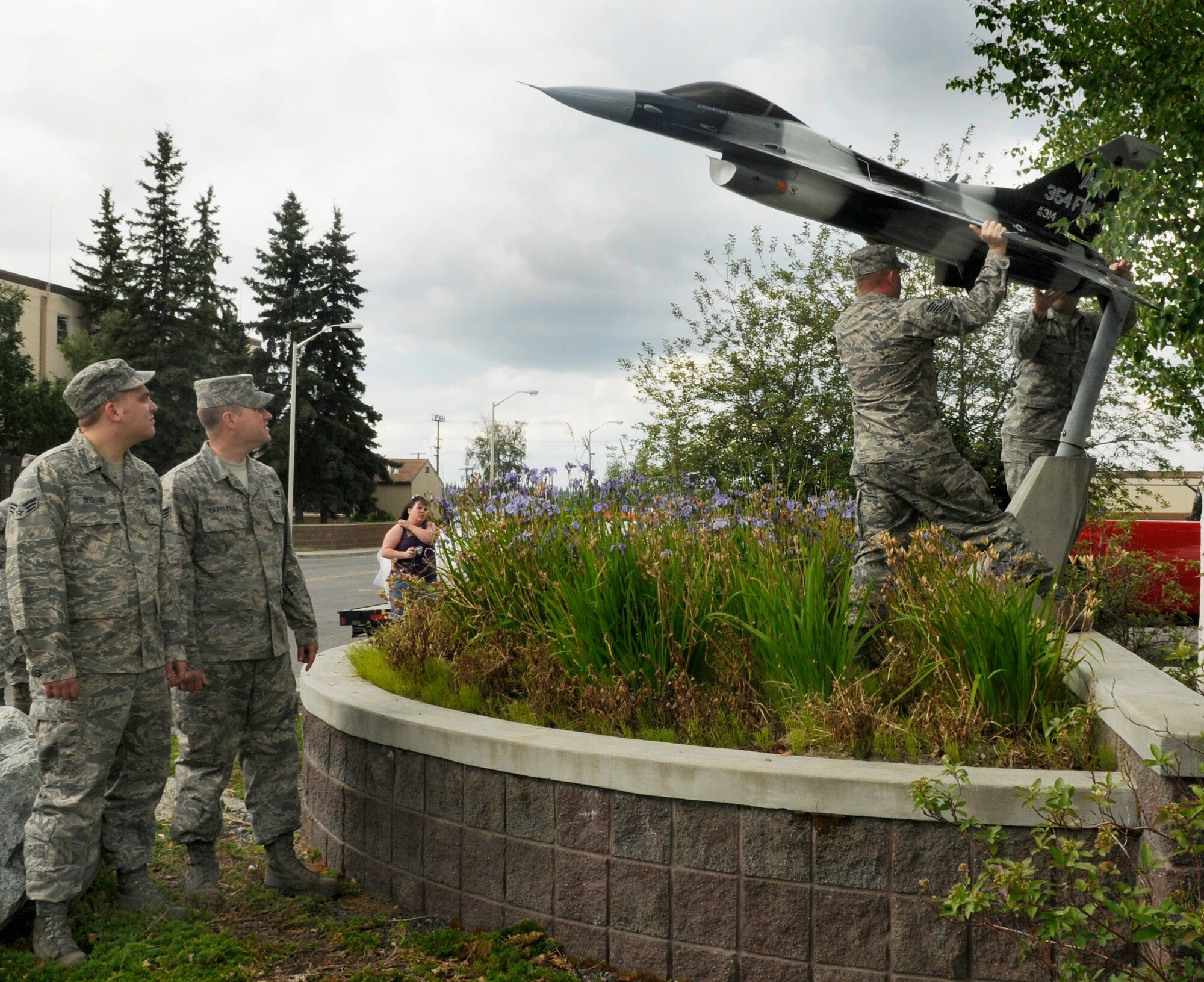 Airmen watch the model F-16 Fighting Falcon being mounted into place in front of Amber Hall June 19, 2009, Eielson Air Force Base, Alaska.The Airmen are assigned to the 354th Maintenance Squadron, Aircraft Structural Maintenance flight. (U.S. Air Force photo/Airman 1st Class Laura Max)

