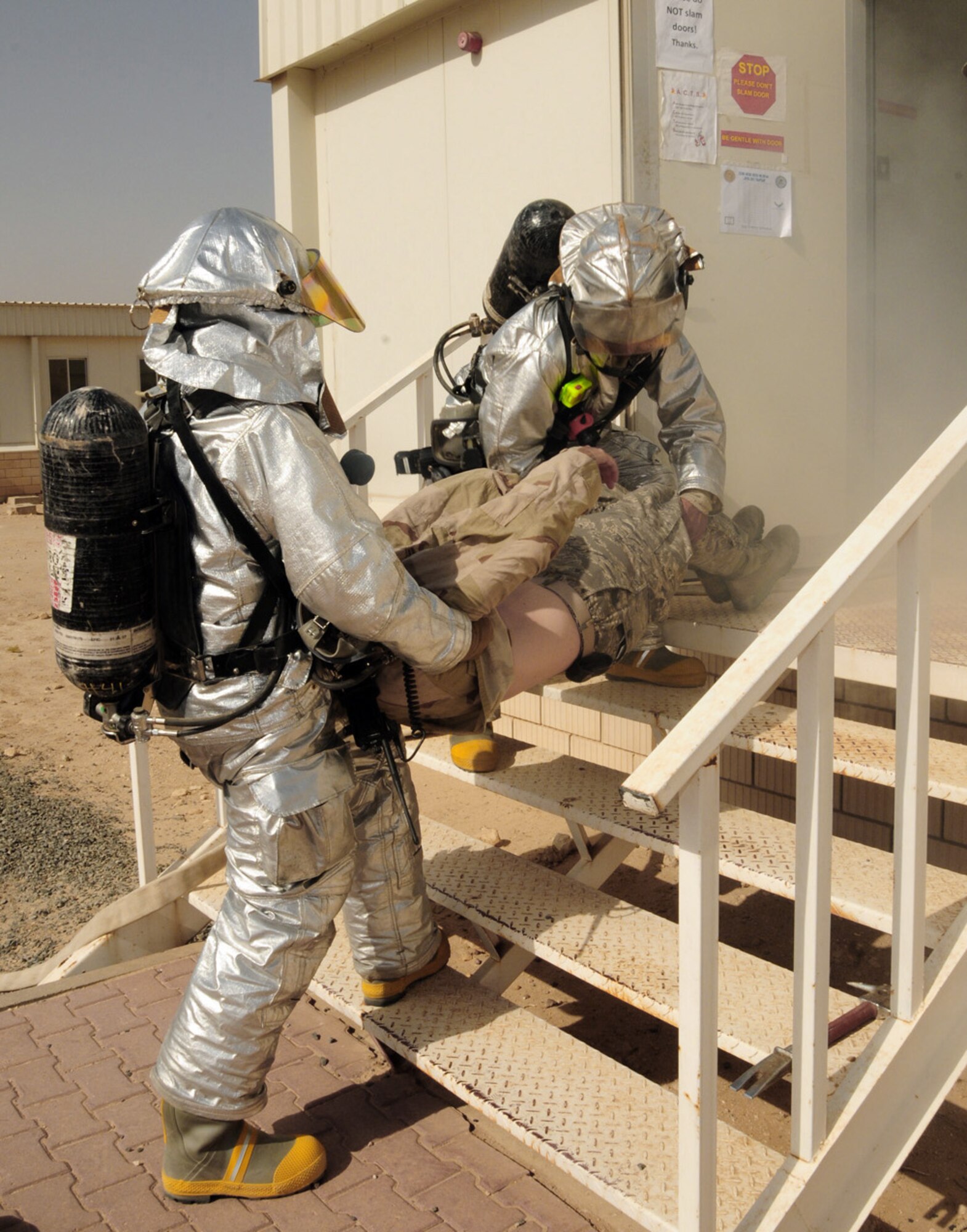 Firefighters from the 386th Expeditionary Civil Engineer Squadron removes a simulated victim from a simulated dorm fire using the two-man fore-and-aft carry during a June 22 exercise at an air base in Southwest Asia. (U.S. Air Force photo/Senior Airman Courtney Richardson)