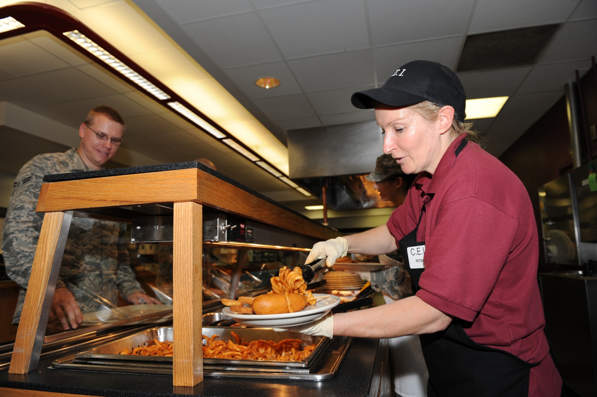 WHITEMAN AIR FORCE BASE, Mo. - Mrs. Petra Purdy, Ozark Inn civilian contractor, serves curly fries and a corn dog to a customer during lunch, June 17. The visitors to the Ozark Inn are particularly fond of the fried items the facility has to offer. (U.S. Air Force Photo/ Airman 1st Class Carlin Leslie)