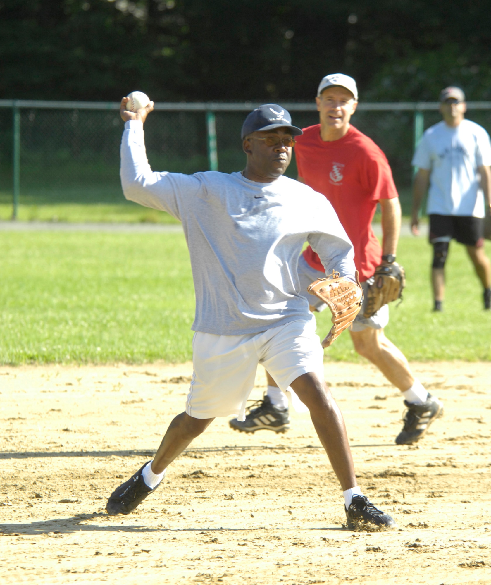 Third baseman Chief Master Sgt. Al Thompson, 66th Security Forces Squadron superintendent, prepares to throw an infield ground ball to first base as teammates Col. Dave Orr, 66th Air Base Wing commander and shortstop, and Master Sgt. Donald Gonsalves, 66th Mission Support Squadron family readiness coordinator and center fielder, look on. Their team, composed of Hanscom's Top Three and colonels, played the softball game to a 16-16 draw against the Hanscom Company Grade Officers.  (U.S. Air Force photo by Mark Herlihy)
