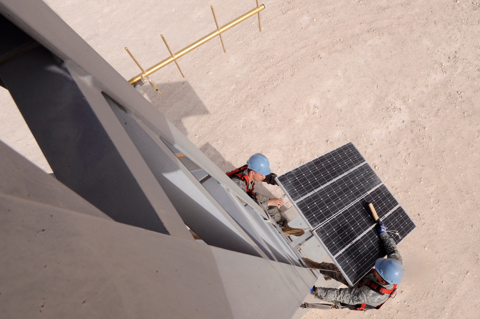 Airmen 1st Class Anthony Arias (left) checks wire connections as Staff Sgt. Jessie Ochs brushes off the solar panel of the giant voice alert system, during a 28 day preventive maintenance inspection, June 22, 2009, at an undisclosed location in Southwest Asia.  The solar panel provides energy to charge the battery that powers the alert system. Both Airmen are ground radio maintainers with the 379th Expeditionary Communications Squadron.  Airman Arias is native to Oakland, Calif. and is deployed from Fairchild Air Force Base, Wash., while Sergeant Ochs hails from Tucson, Ariz. and is deployed from the Arizona Air National Guard, both in support of Operations Iraqi and Enduring Freedom and Combined Joint Task Force - Horn of Africa.  (U.S. Air Force Photo by Staff Sgt. Joshua Garcia/released)