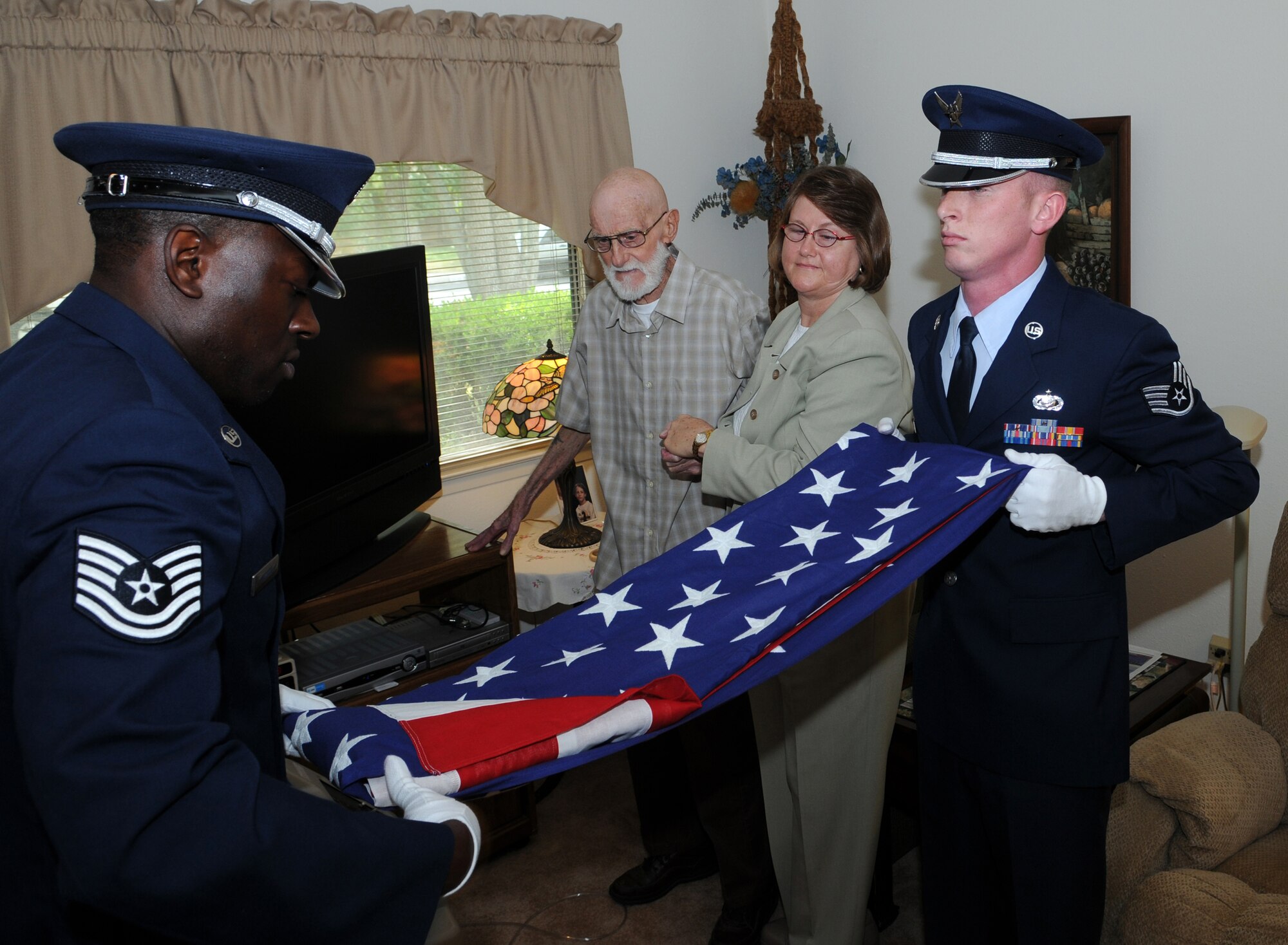 Tech. Sgt. Michael Nelson and Staff Sgt. Shane Antrim, Air Force Personnel Center, fold a flag before presenting it to retired Tech. Sgt. Billy Oldham in honor of his many years in service to his country. Randolph Air Force Base Airmen volunteered to perform the special ceremony at the request Sergeant Oldham?s daughter, Sherrill. (U.S. Air Force photo by Don Lindsey)
