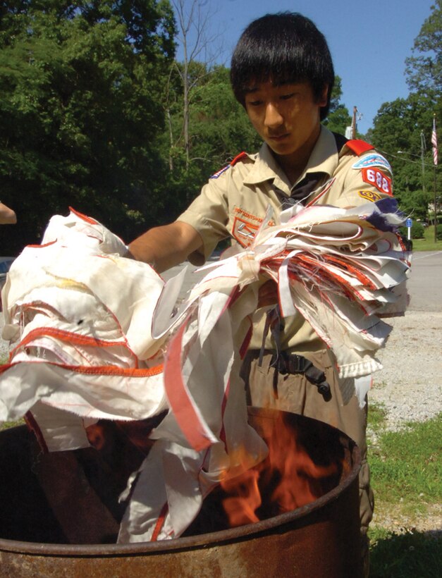 Bryce Ferrell, 15, son of Ryan Ferrell, Air Force District of Washington director of personnel services and management, tosses a bundle of white flag strips into a fire. (U.S. Air Force photo/ Bobby Jones)