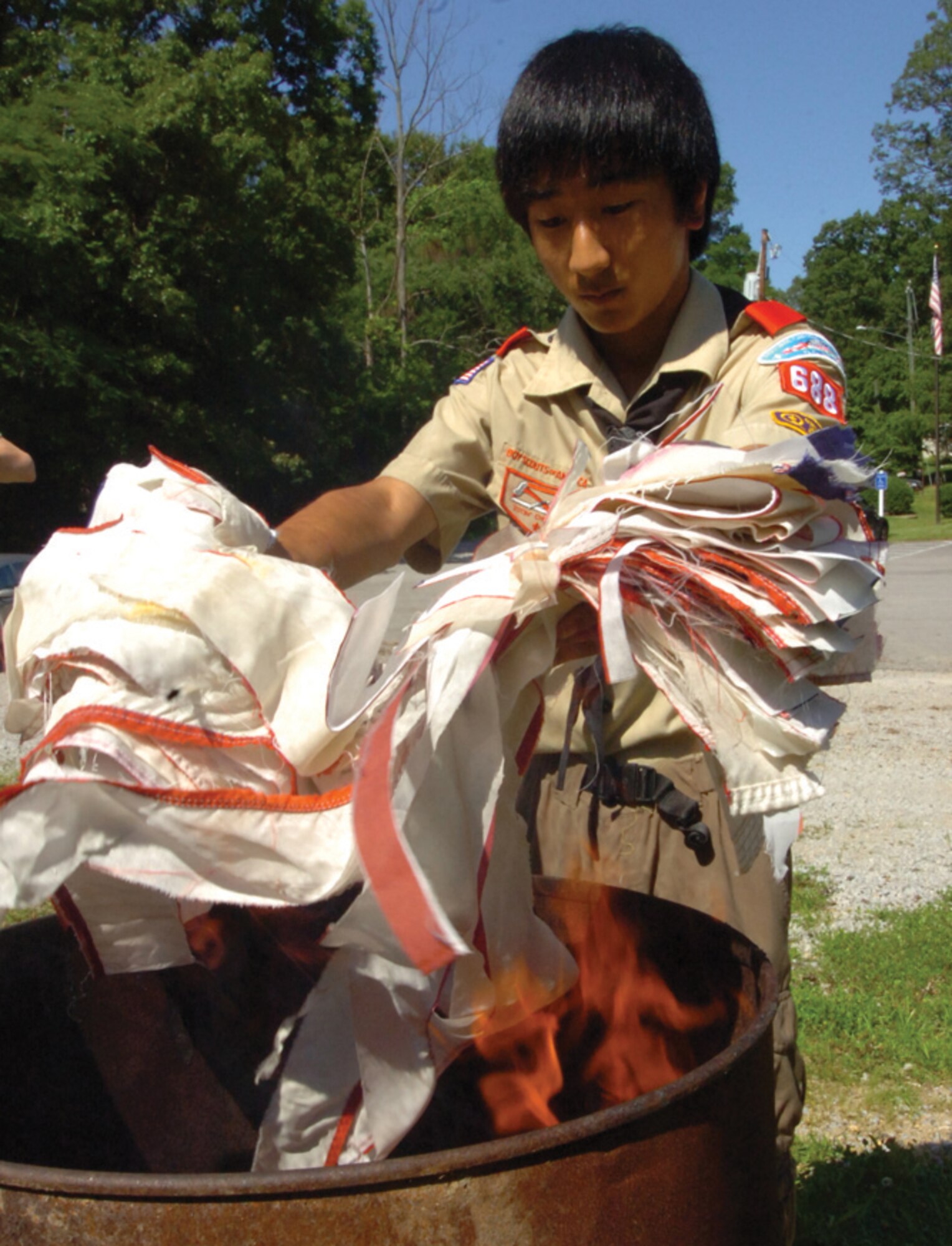 Bryce Ferrell, 15, son of Ryan Ferrell, Air Force District of Washington director of personnel services and management, tosses a bundle of white flag strips into a fire. (U.S. Air Force photo/ Bobby Jones)