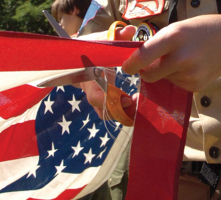 A troop member cuts a stripe from the U.S. flag during the official flag retirement ceremony. (U.S. Air Force photo/ Bobby Jones)
