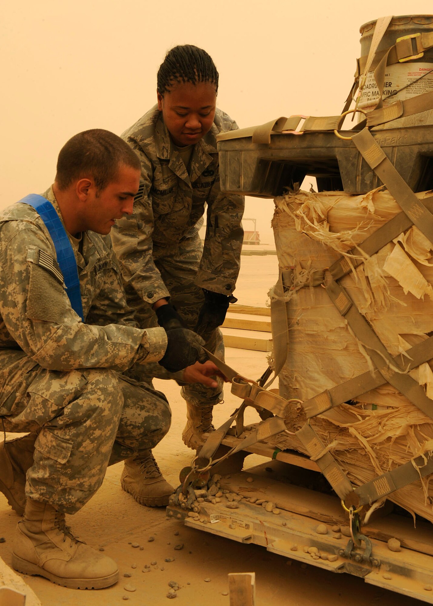 Army Sergeant Josiah Rubi, 258th Movement Cargo Team, shows Staff Sgt. Starlette McMillan, 22nd Movement Control Team, how to properly place a strap on cargo netting so it can be tightened correctly at Sather Air Base, Iraq June 18, 2009. Sergeant McMillan is a part of a 16-person team taking over the mission from the Army’s 258th MCT. Sergeant Rubi is deployed from Hunter Army Airfield, Savannah, Ga. and a native of Winslow, Ariz. Sergeant McMillan is deployed from Fairchild Air Force Base, Wash., and a native of Silverdale, Wash.  (U.S. Air Force photo by: Senior Airman Jacqueline Romero)
