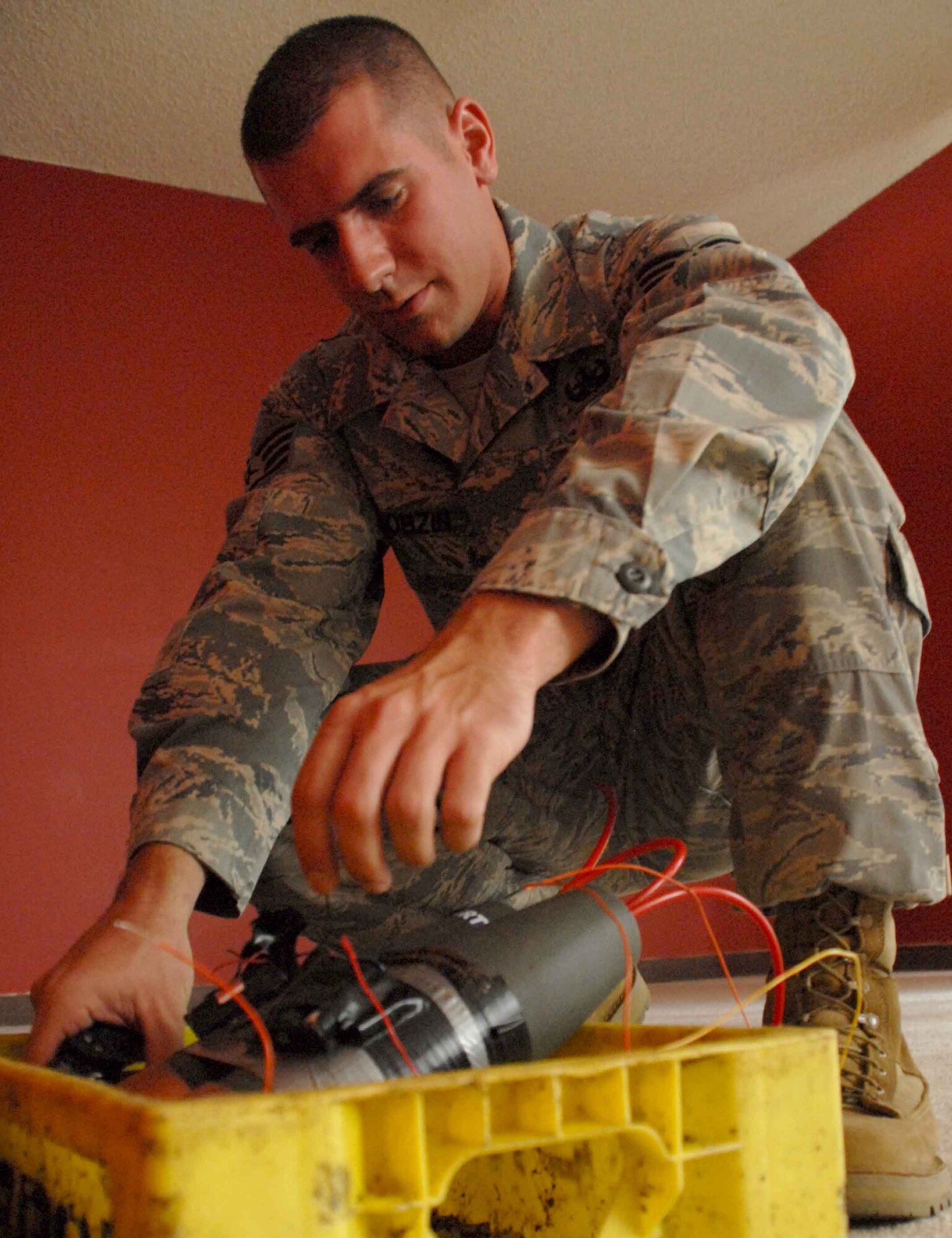 HICKAM AIR FORCE BASE, Hawaii – Staff Sgt. Ryan Bobzin, 15th Civil Engineer Squadron explosive ordnance disposal technician, rigs an improvised explosive device inside a booby-trapped house on base June 22. As part of regular training, EOD team leaders send a robot in the house to assess the situation and detonate or disarm the IEDs before sending a team member into the building with a bomb suit. They take situations previously encountered in deployed locations and make them harder than real life so that when they get to the field they’re prepared for anything.  (U.S. Air Force photo/Senior Airman Carolyn Viss)