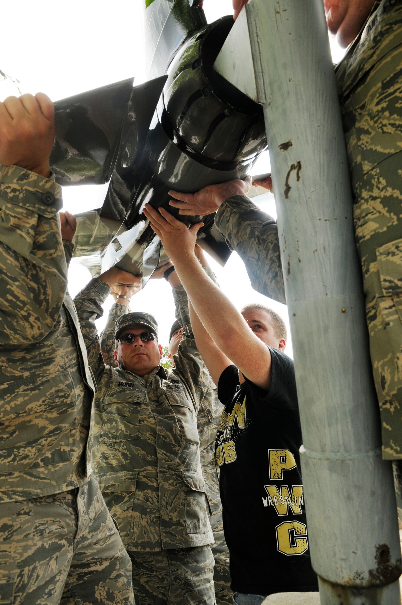 Airmen work together to place a model aircraft onto a bracket June 19, 2009, Eielson Air Force Base, Alaska. The model was repainted with arctic camouflage to match the 18th Aggressor Squadron aircraft. The Airmen are assigned to the 354th Maintenance Squadron, Aircraft Structural Maintenance flight.   (U.S. Air Force photo/Airman 1st Class Laura Max)