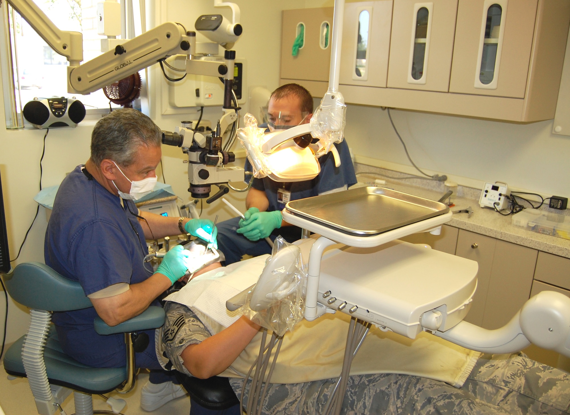 Lt. Col. (Dr.) Gerald Kaban, left, and Senior Airman Eric Robbins perform a root canal in the dental clinic.