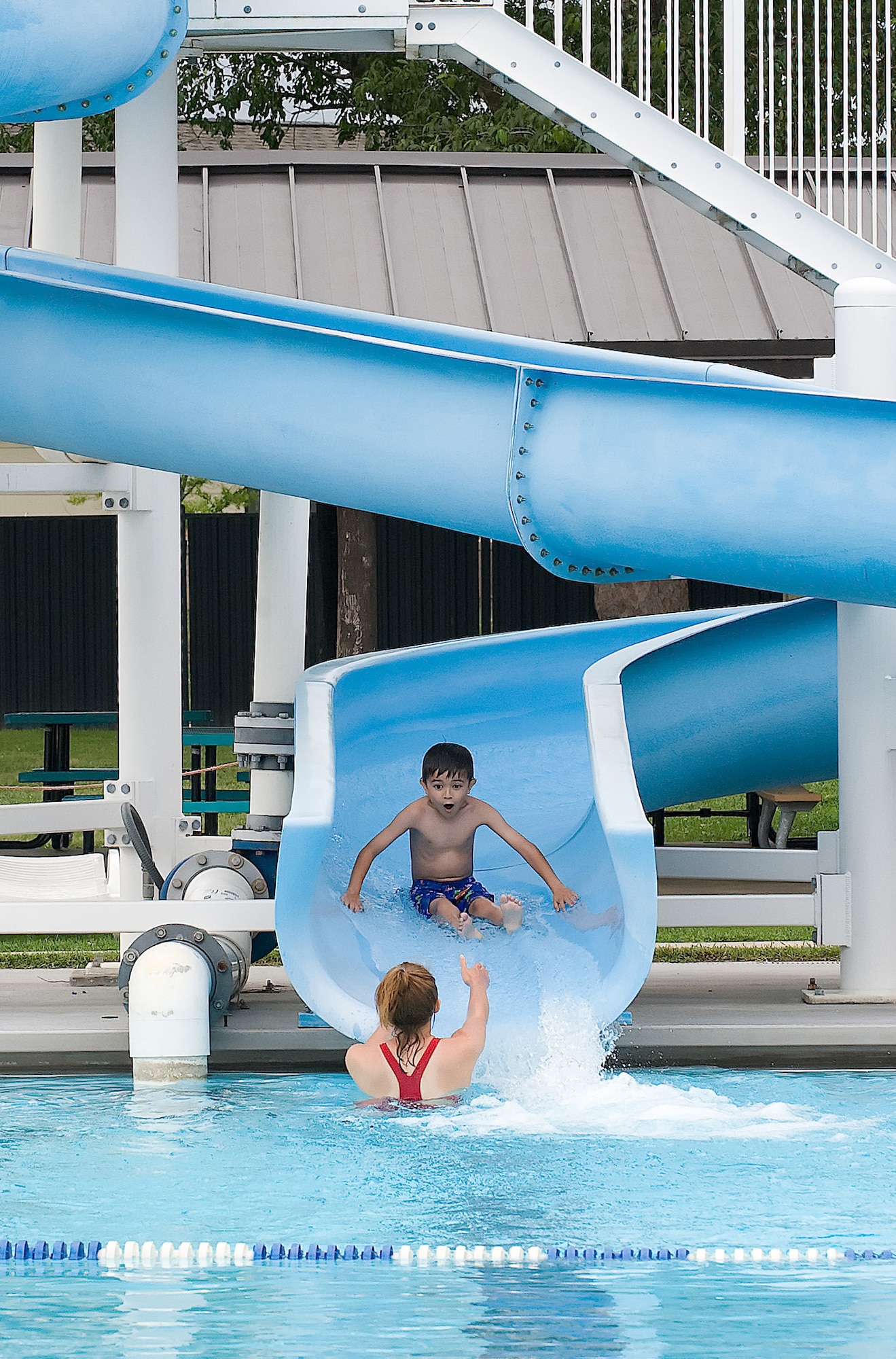 Emily Kolakowski, an Oasis Pool swimming instructor, prepares to catch Liam Wallace, one of her students, as he glides down their water slide at Dover Air Force Base June 23. The children get to finish their daily half hour swimming lesson with a fun-filled splash on the slide. (U.S. Air Force photo/Tom Randle)