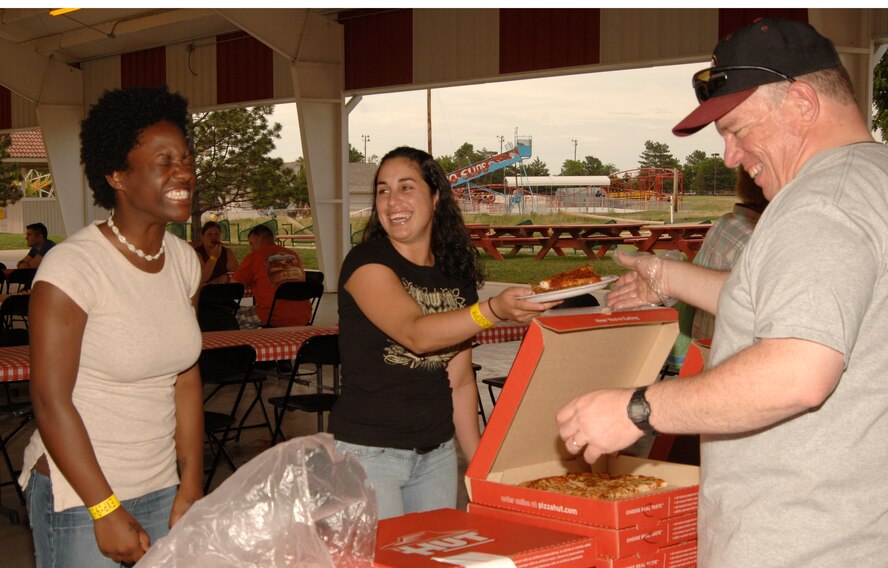 MCCONNELL AIR FORCE BASE, Kan. -- Senior Airman Nia Adams and Airman 1st Class Oria Acosta, 22nd Communications Squadron, exchange smiles for pizza with Senior Master Sgt. Raymond Pelletier, 22nd Operations Support Squadron, during the All Star Adventure family evening, June 19. Sergeant Pelletier and other members of the McConnell Chief’s Group sponsored and organized the event. (Photo by Senior Airman Laura Suttles)