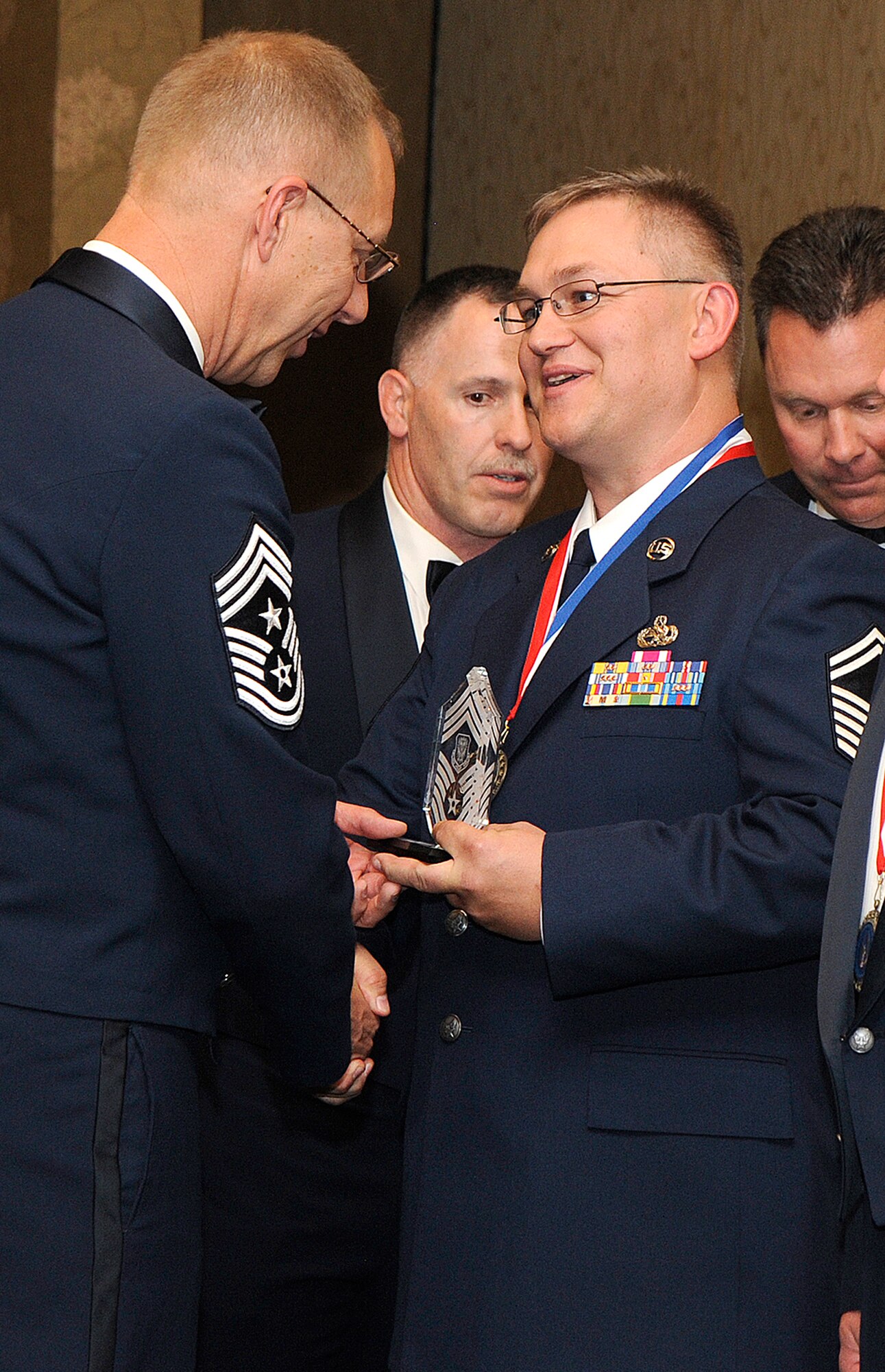 Chief Master Sgt. Joe Westerlund presents glass-encased chief master sergeant stripes to Senior Master Sgt. Garrin Pies June 13 during a chief's recongition ceremony at the Crowne Royal Plaza in Colorado Springs, Colo. The awards and congratulations by their peers were presented to each recently-promoted chief master sergeant of both the 310th Space and 302nd Airlift Wings. Those senior master sergeants recently promoted the rank of "chief" were recognized during the joint 310th SW-302nd AW event. Both wings are assigned to the Air Force Reserve. Sergeant Pies is the 302nd Maintenance Group quality assurance superintendent. (U.S. Air Force photo/Craig Denton)
