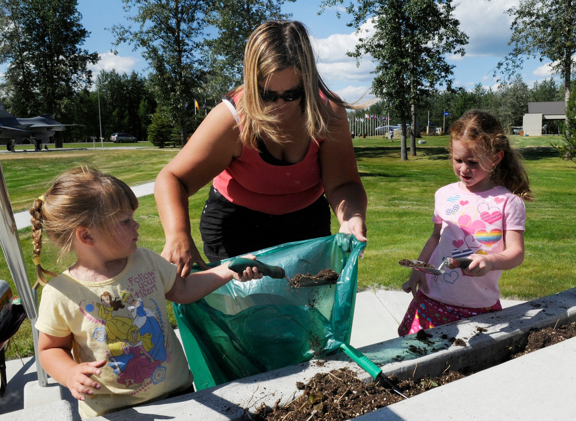 Shannan Lam, Brooke Lam, and Sara Flick clean out a flower pot 17, 2009, Eielson Air Force Base, Alaska. The Enlisted Spouses Club is planting flowers as part of a beautification project at Heritage Park. Shannan and Brooke are the family of Master Sgt. Gary Lam, NCO in Charge of Weather Flight and Sara is the daughter of Maj. Dale Flick with the 18th Aggressor Squadron.(U.S. Air Force photo/Airman 1st Class Laura Max)