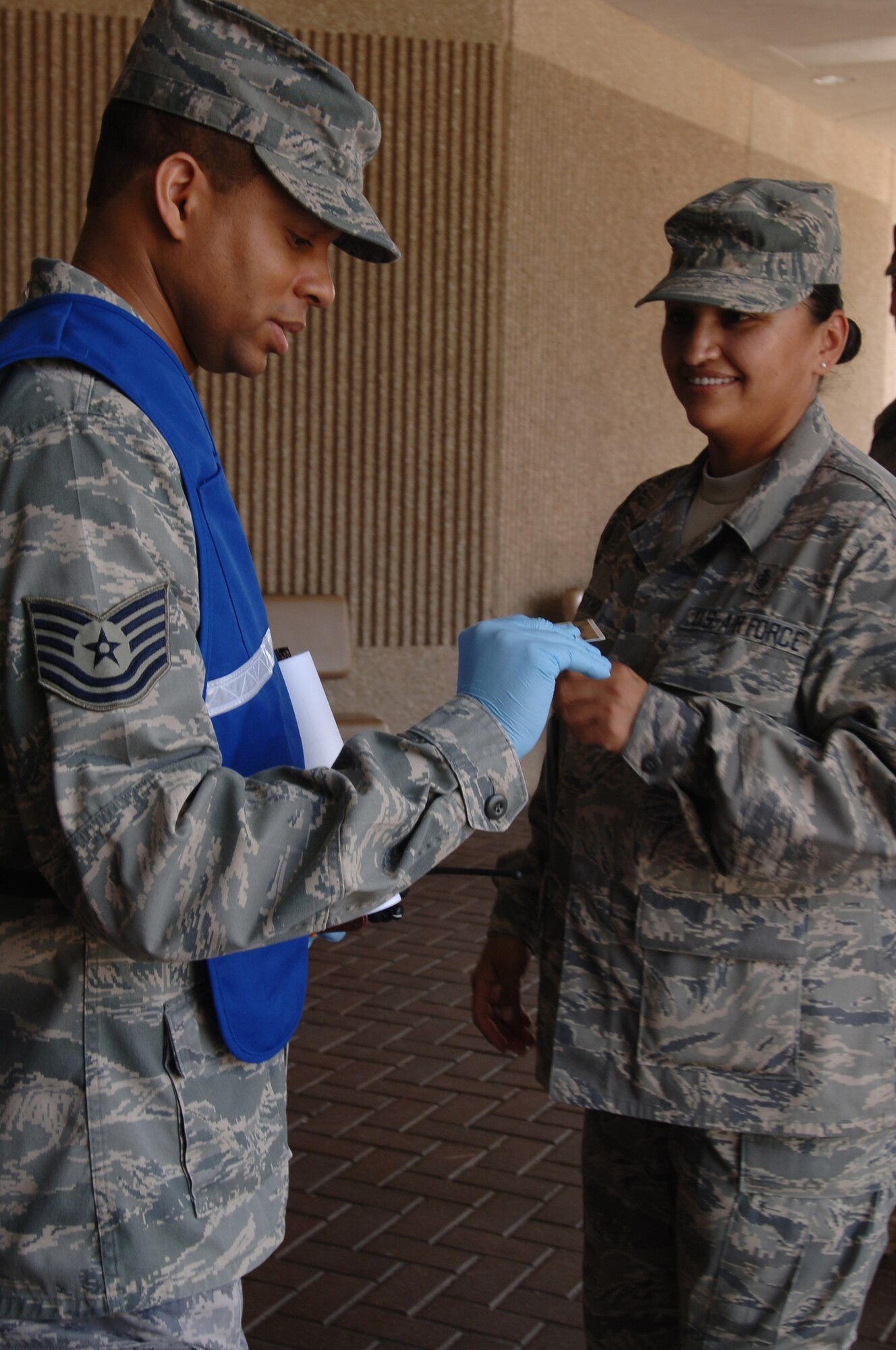 Tech. Sgt. Robert Little, NCO-in-charge of Document Control, 59th Medical Logistics and Readiness Squadron (left), checks Staff Sgt. Carlotta Monetathch's identification during a Force Protection Condition Exercise June 17 at the Wilford Hall Medical Center Emergency Department entrance, Lackland Air Force Base, Texas.  The Force protection conditions were one of the areas inspected during the Unit Compliance Inspection.  (U.S. Air Force photo by Senior Airman Nicole Roberts)  