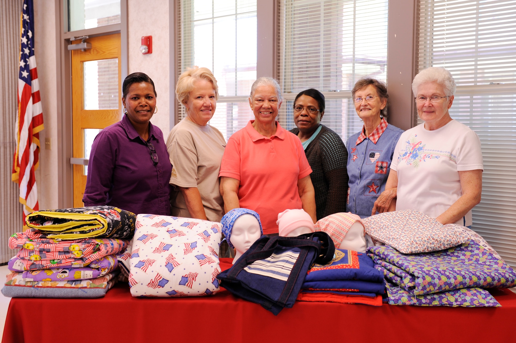 Sewing Ministry members (from left) Helen Davis, Bobbie Waddell, Ora Brown, Victoria Deramus, Barbara Hamm and Rachel Whiting displays the crafts created by the club members. The club makes blankets, hats and other domestic goods for needy recipients. (U.S. Air Force photo by Airman Lausanne Pacheco)
