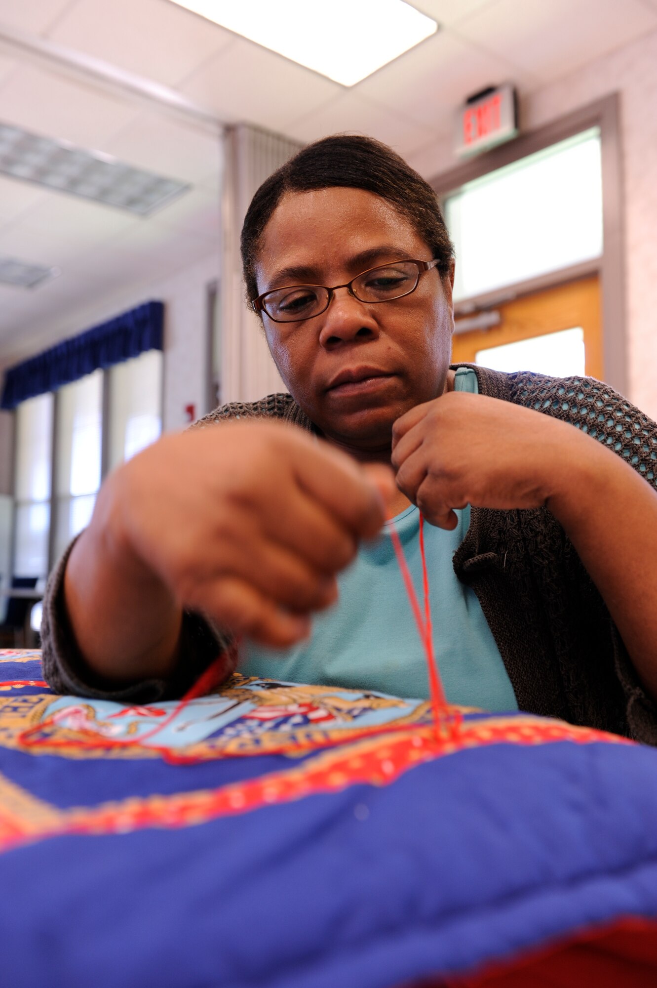 Ms. Victoria Deramus puts the finishing touches on a blanket sewn by the Sewing Ministry at the Chapel Annex Friday. The club makes blankets, hats and other domestic goods for needy recipients. (U.S. Air Force photo by Airman Lausanne Pacheco)