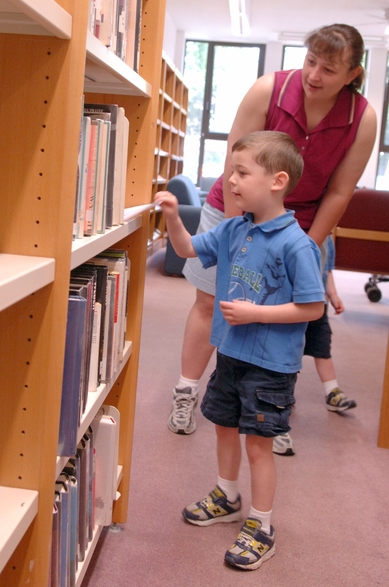 Brian Evans (front), son of U.S. Air Force Tech. Sgt. Jason Evans, U.S. Air Forces in Europe, and his aunt, Myra Fehr, find a piece of a dinosaur puzzle hidden among the library books, June 18, 2009, Ramstein Air Base, Germany. Evans, along with other children, hunted for puzzle pieces during story time as part of the summer reading program. (U.S. Air Force photo by Senior Airman Amanda Dick)