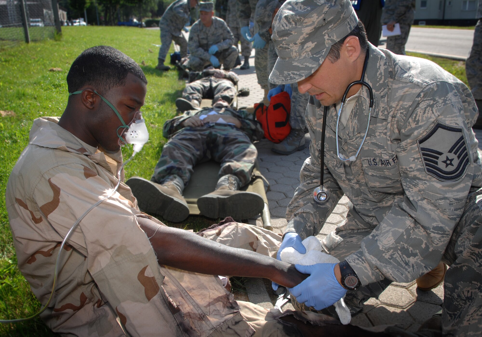 SPANGDAHLEM AIR BASE, Germany – Master Sgt. Troy Long, 134th Medical Group, McGhee-Tyson Air National Guard, Tenn., medical technician, treats Airman Eric Haygood, 52nd Equipment Maintenance Squadron Emergency Evaluations Team volunteer, for simulated injuries. The players, volunteers and the medical response team in the background, are all part of an emergency management exercise with a simulated F-16 crash involving by-standers June 23. (U.S. Air Force photo by Master Sgt. Bill Gomez) 