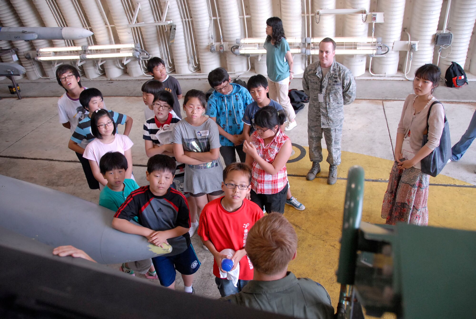 Capt. Kristopher Holstege, (center), gives an explanation of the F-16 aircraft to students from the Seojenongri Elementary School during their visit to Osan AB June. 19. Airmen from the 51st Dental Squadron and Operations Group here joined together to Adopt-A-School for a day and gave them a tour of the base and flightline. Captain Holstege is a member of the 36th Fighter Squadron. (U.S. Air Force photo/Master Sgt. Marlin Zimmerman)
